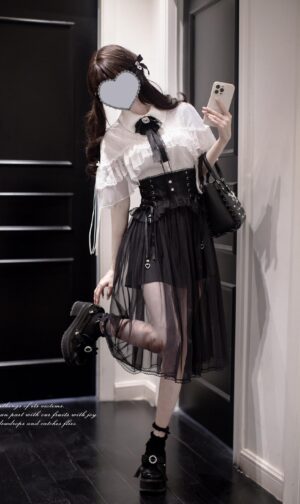 Front three-quarter view of ethereal Jirai Kei cape blouse and high-waist tulle skirt set with ruffled white cape, black corset waist, sheer overlay, and rhinestone bow tie accessory on faceless model