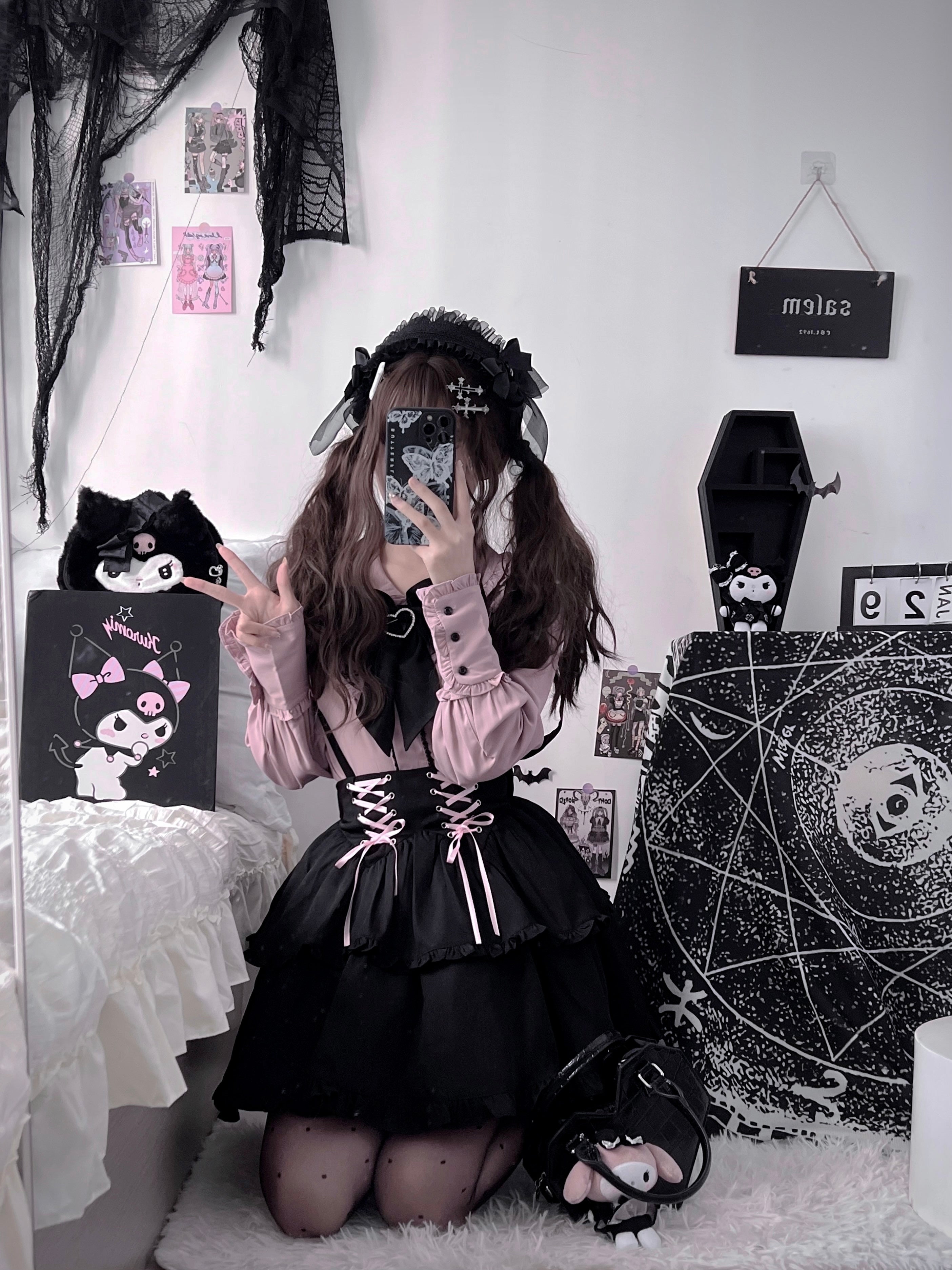 Kneeling full-body Jirai Kei selfie wearing polka dot tights, black tiered suspender skirt, pink lace-up waist, gothic coffin wall decor background