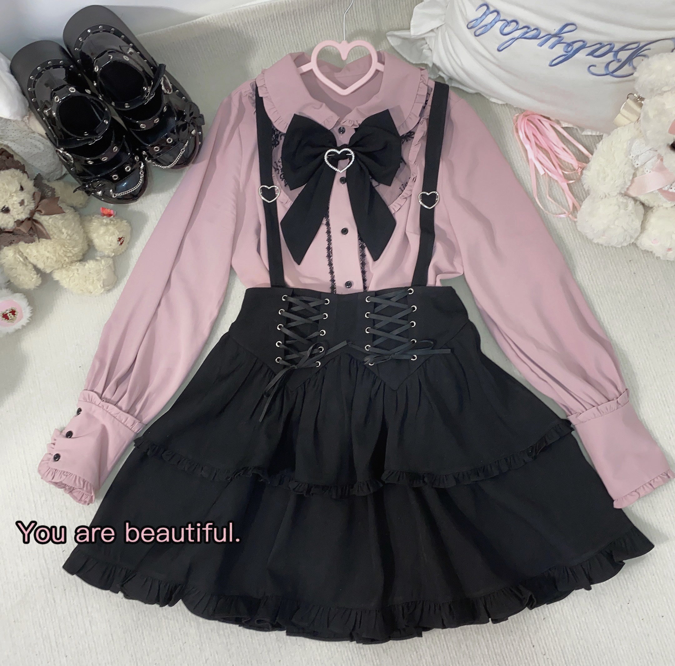 Full-body Jirai Kei outfit featuring long-sleeved dusty pink blouse with Peter Pan collar, black ruffled lace-up suspender skirt, gothic aesthetic styling