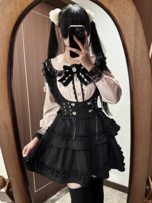 Jirai Kei blouse and black suspender skirt full outfit shown on model wearing twin tails hairstyle and white pompom clips in home mirror selfie setting