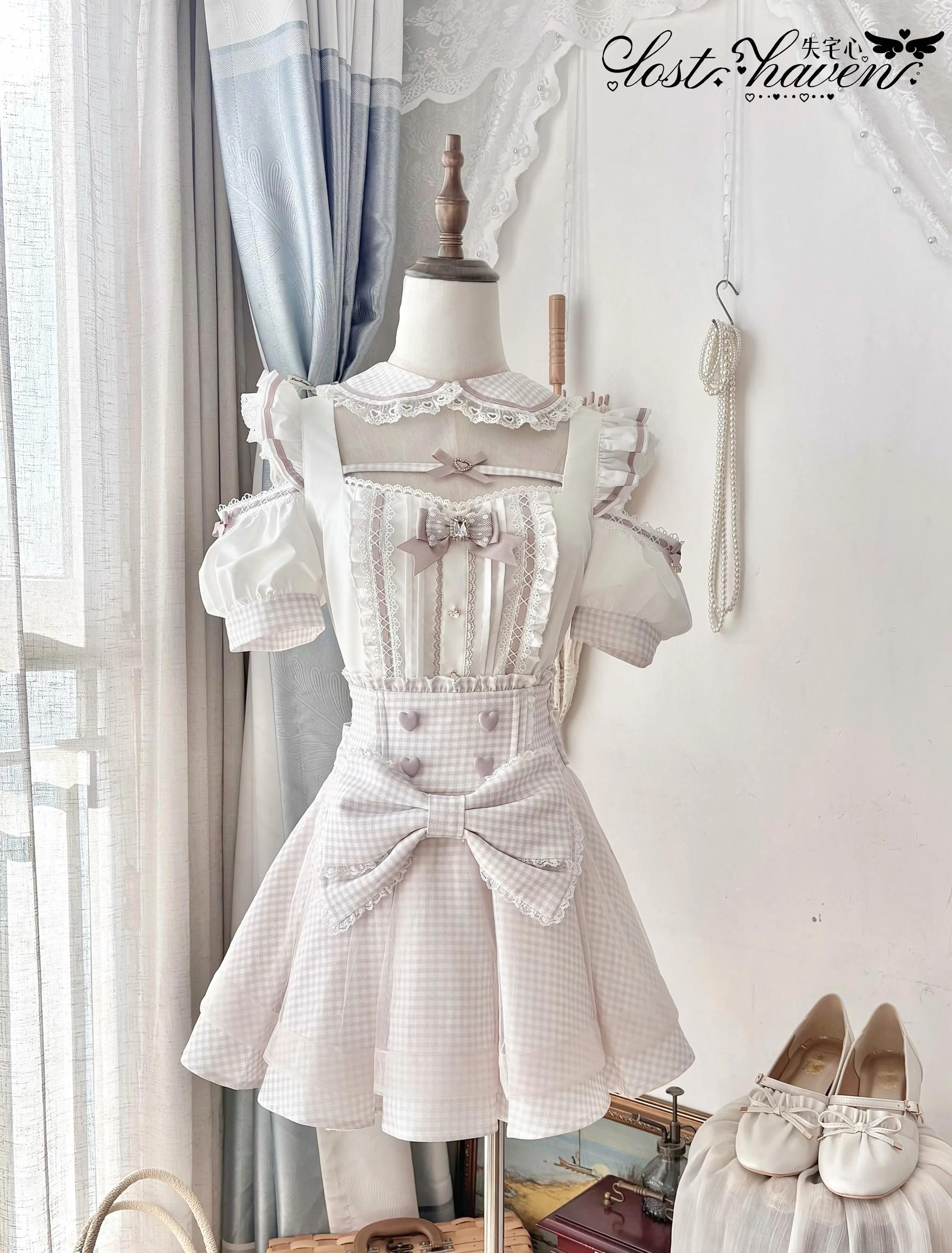 Front display view of pink gingham Jirai Kei maid outfit set with lace trim, large decorative waist bow, and detachable apron by window light