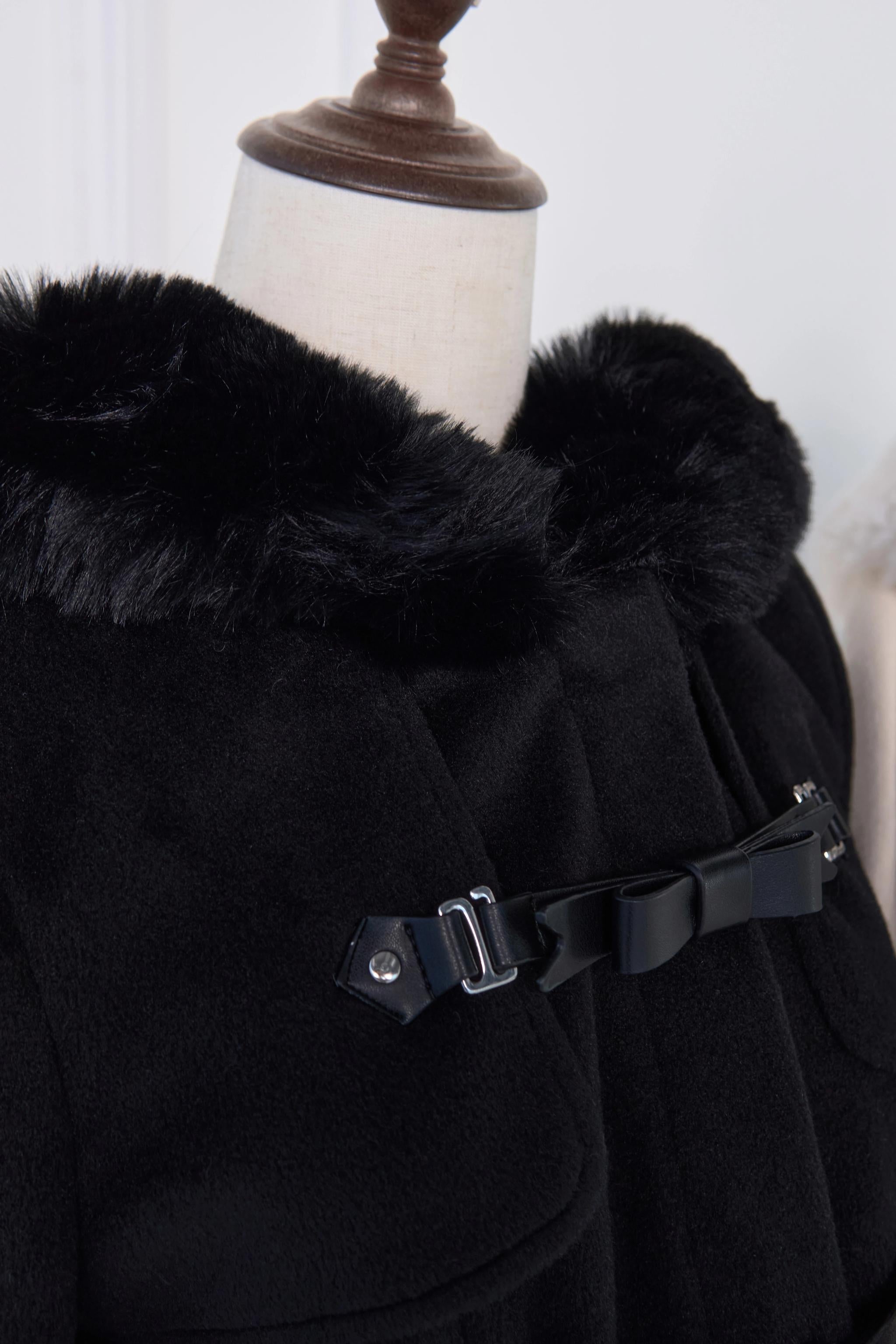 Close-up detail of black hooded rousangata coat showing black fur collar, leather bow-accent buckle, and premium construction details of jirai kei statement piece