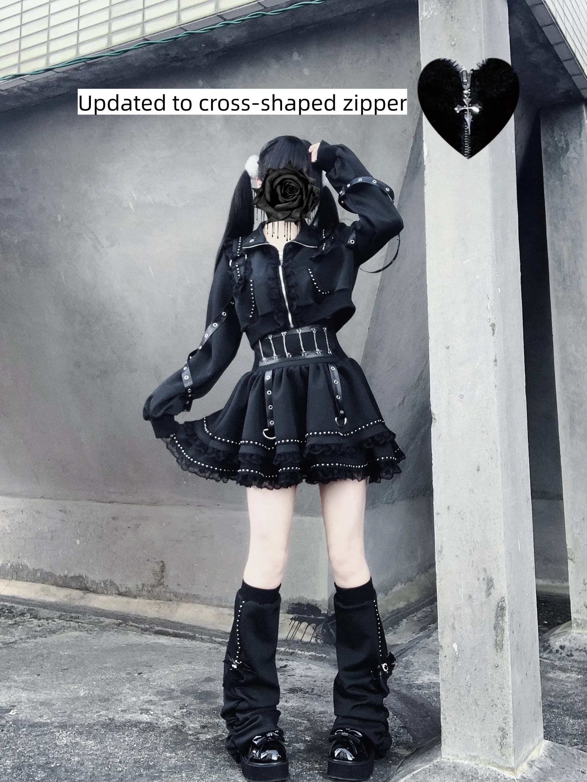 Side three-quarter view gothic punk jacket and skirt with cross-shaped zipper lace ruffle hem leg warmers boots buckle belt concrete wall outdoor