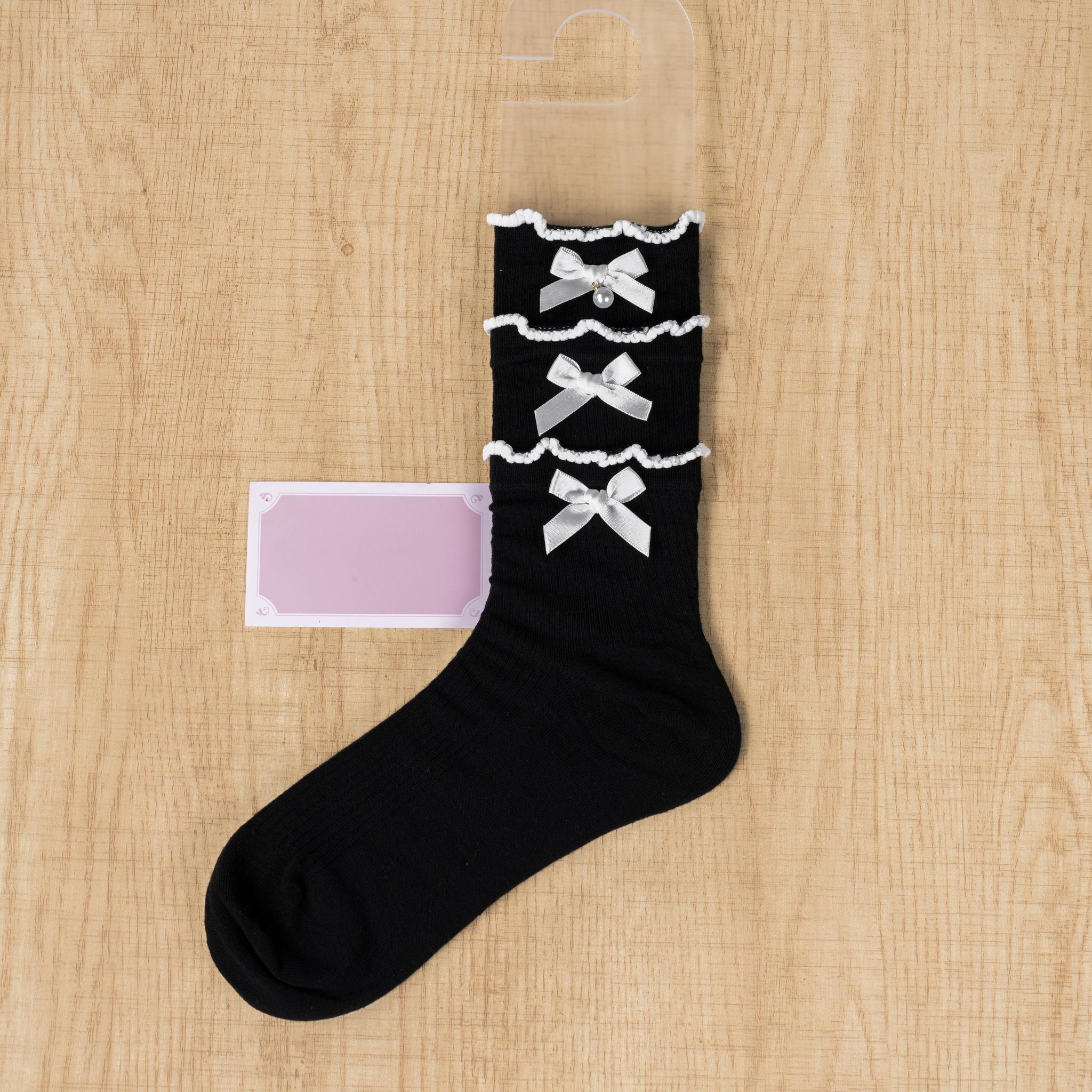 Black and pink triple-layered lace mid-calf Jirai Kei socks with white satin bows and ruffled cuffs flat lay product shot
