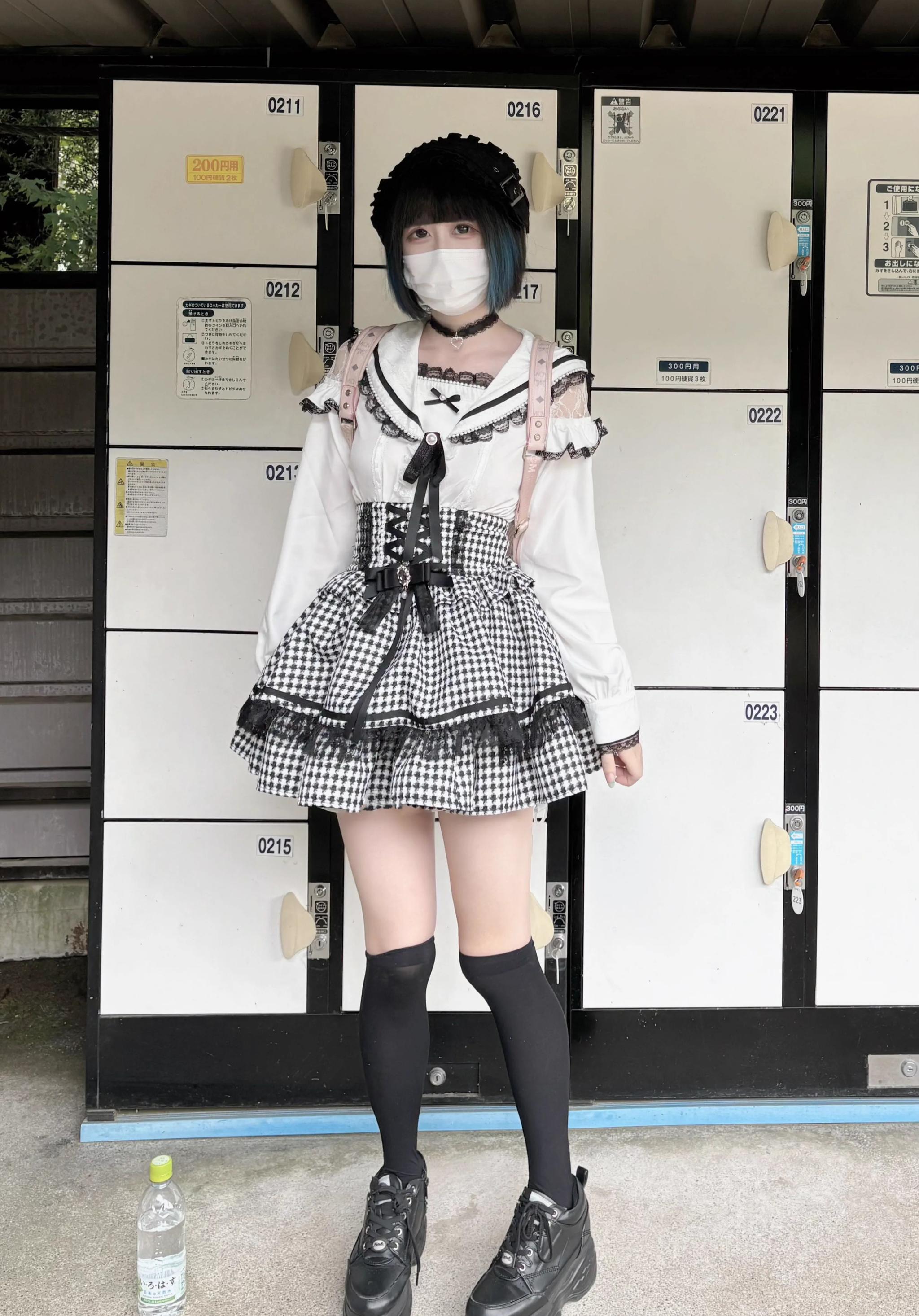 Single masked female model wearing long-sleeved Jirai Kei sailor collar blouse with front bow detail and thigh-high socks positioned by urban lockers, demonstrating structured sailor collar design and extended sleeve length