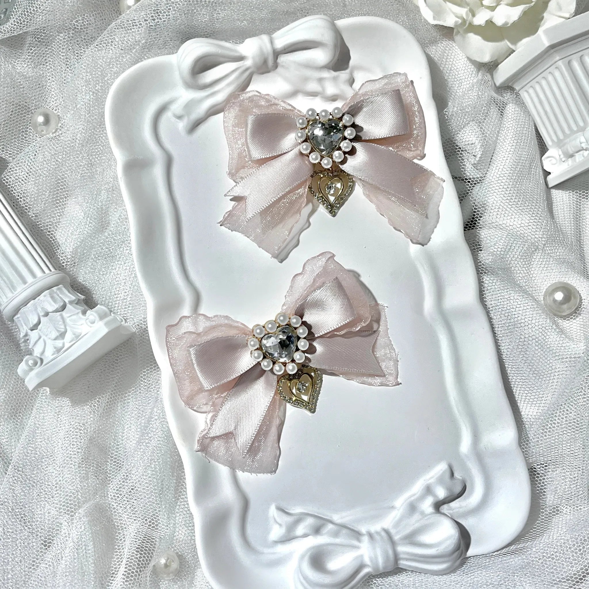 Dusty pink bow hair clips for Jirai Kei fashion style with ornate rhinestone accents and heart dangles macro photography detail