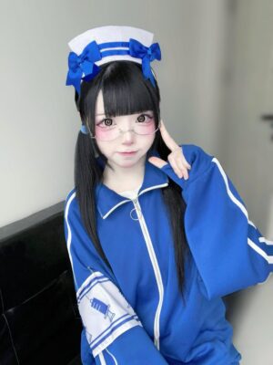 Close-up detail of blue track jacket with printed arm patch and nurse-style headwear indoor room setting