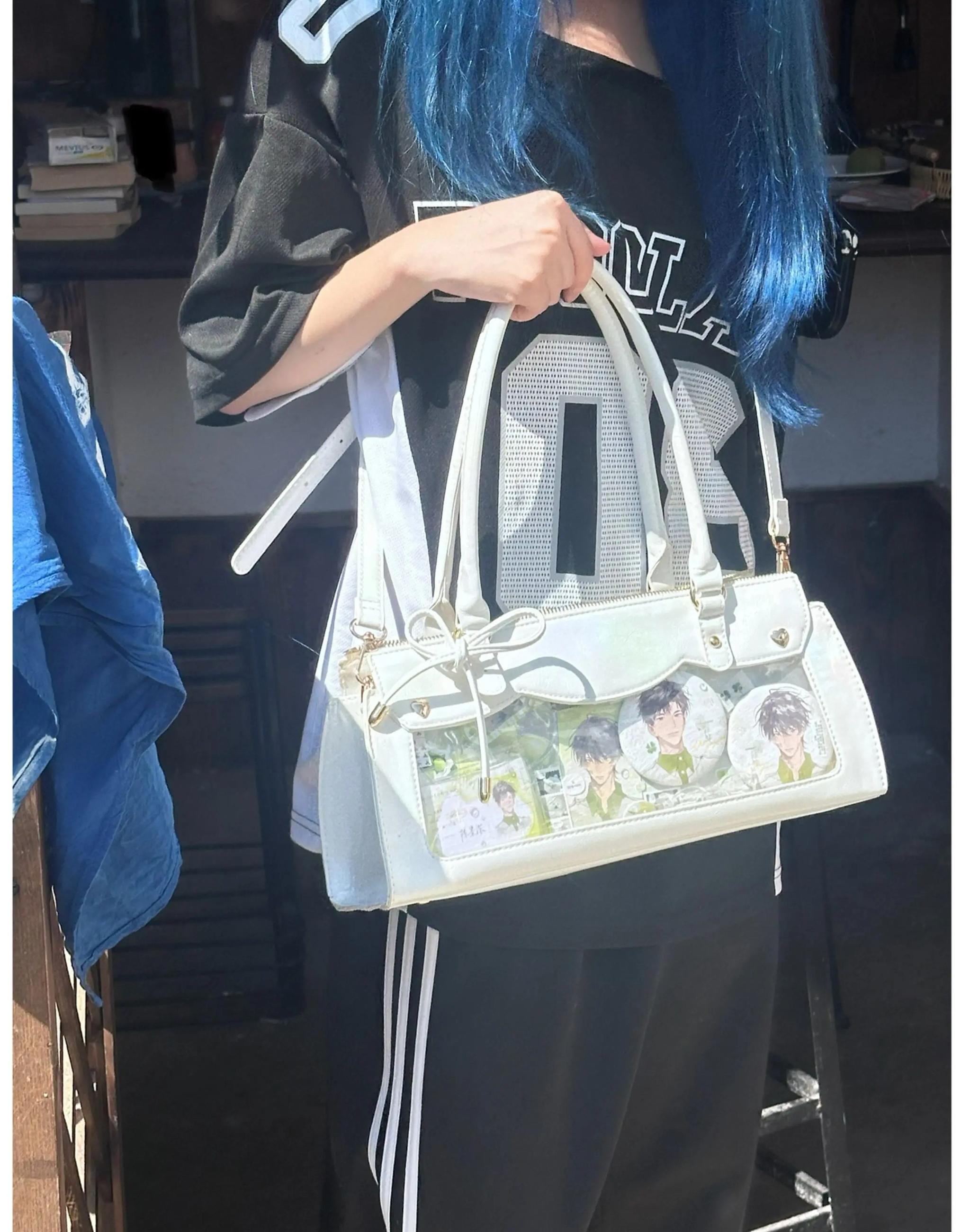 White and light blue baguette itabag with bow decoration and anime card display, indoor daily background front angle