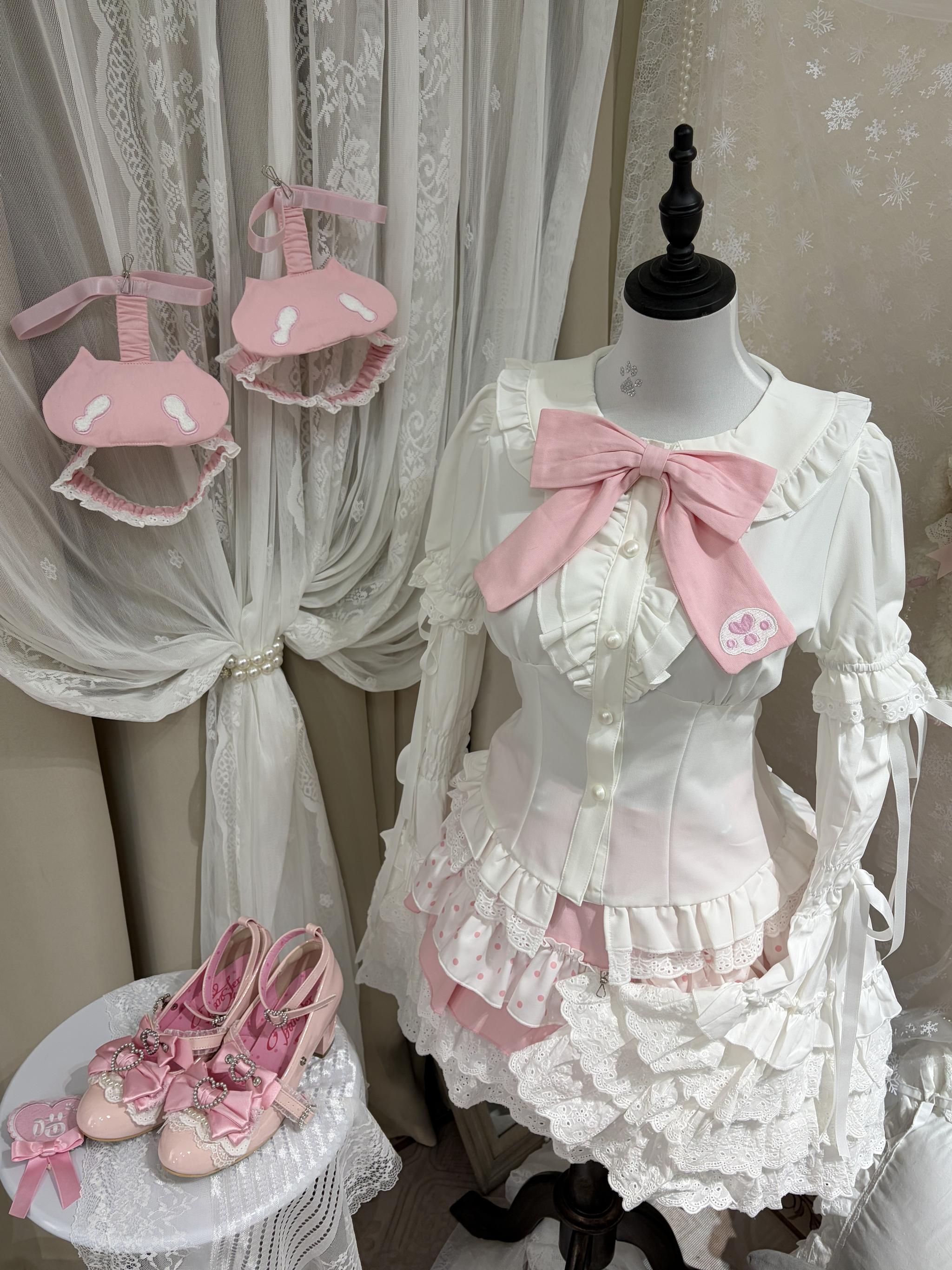 Lolita short sleeve shirt with bow and ruffled details, jirai kei style blouse with pink bow collar and decorative lace trims, flat lay product display view
