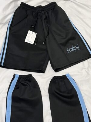Black Tenshi Kaiwai shorts set with light blue side stripes and embroidered details on smooth white background, flat lay view showing brand tag attachment and drawstring waist construction