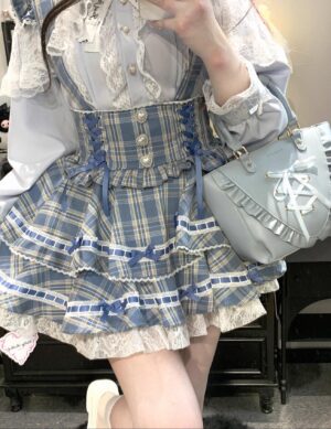 Blue plaid Jirai Kei suspender skirt with tartan pattern and lace ruffled hem featuring ribbon detailing and decorative buttons close-up view