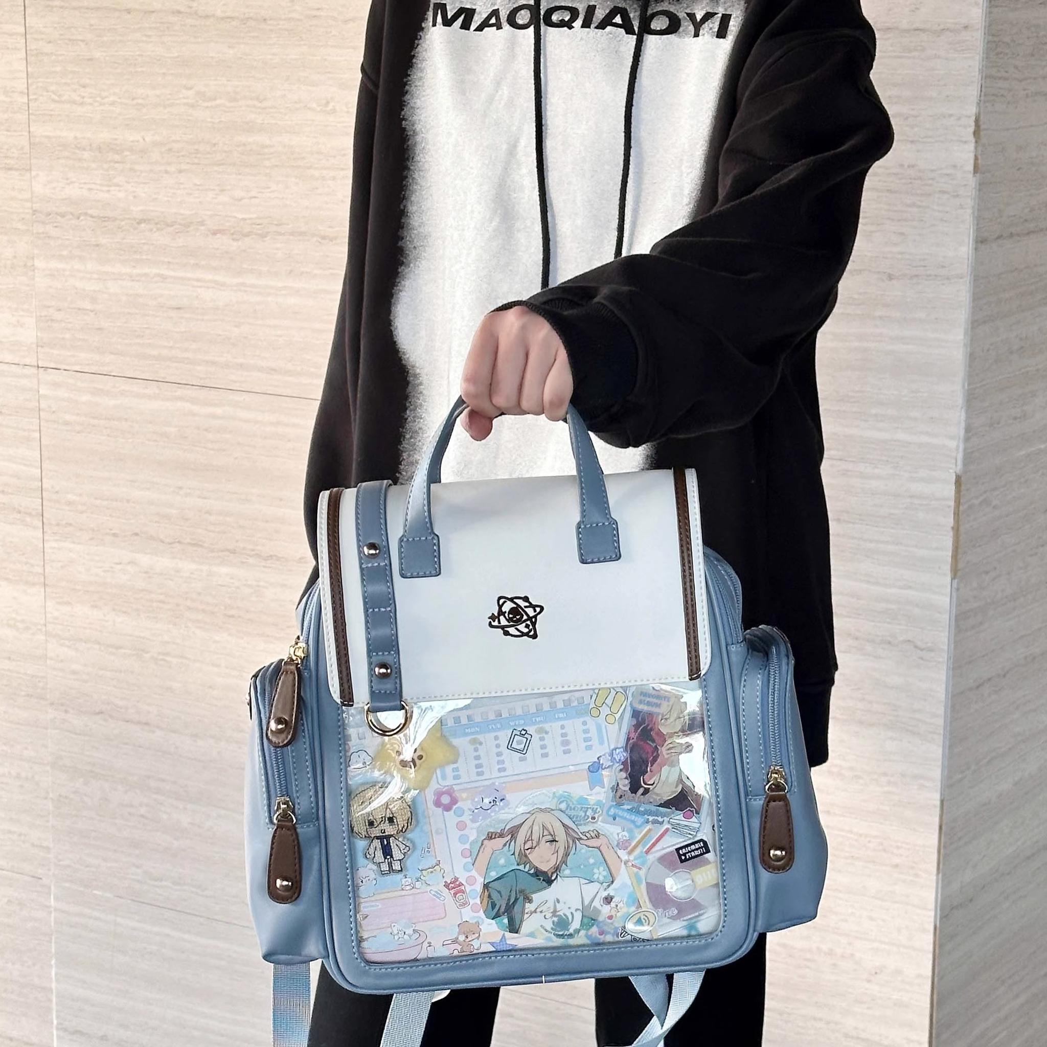 Itabag backpack product detail shot showing transparent display window and embroidered flap embellishments close-up
