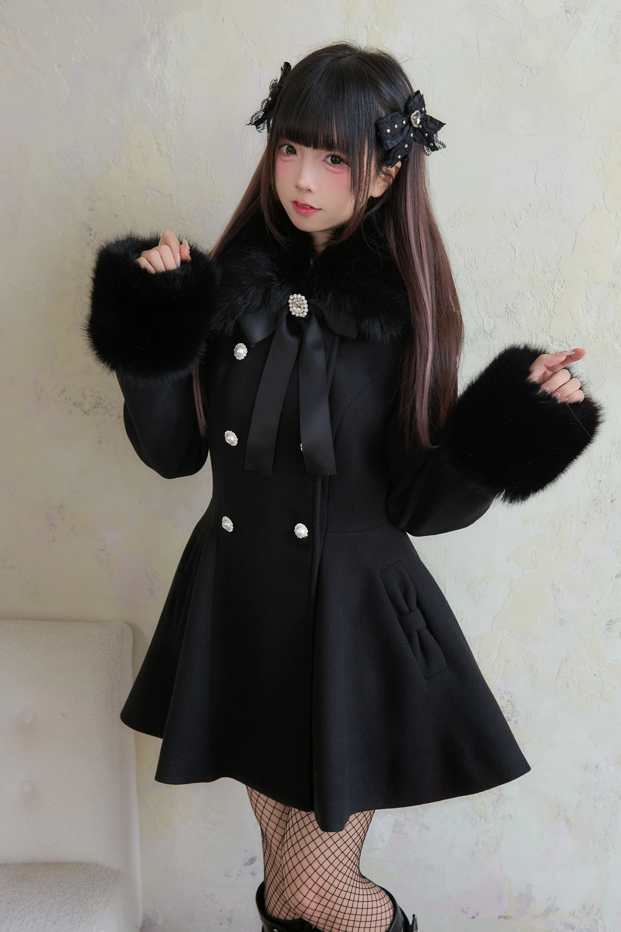 Low-angle front view of black Jirai Kei winter coat displaying oversized faux fur cuffs wide fur collar and silver-toned button details
