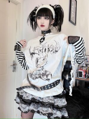Full-body front view of black-white striped jirai kei fake two-piece long sleeve punk tee with cartoon cat graphic print, worn with studded belt and gothic twin-tail hairstyle