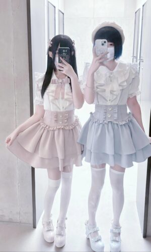 Two real female models in jirai kei two-piece sets with high-waisted corset waistbands, white sheer stockings, full-length boutique mirror selfie