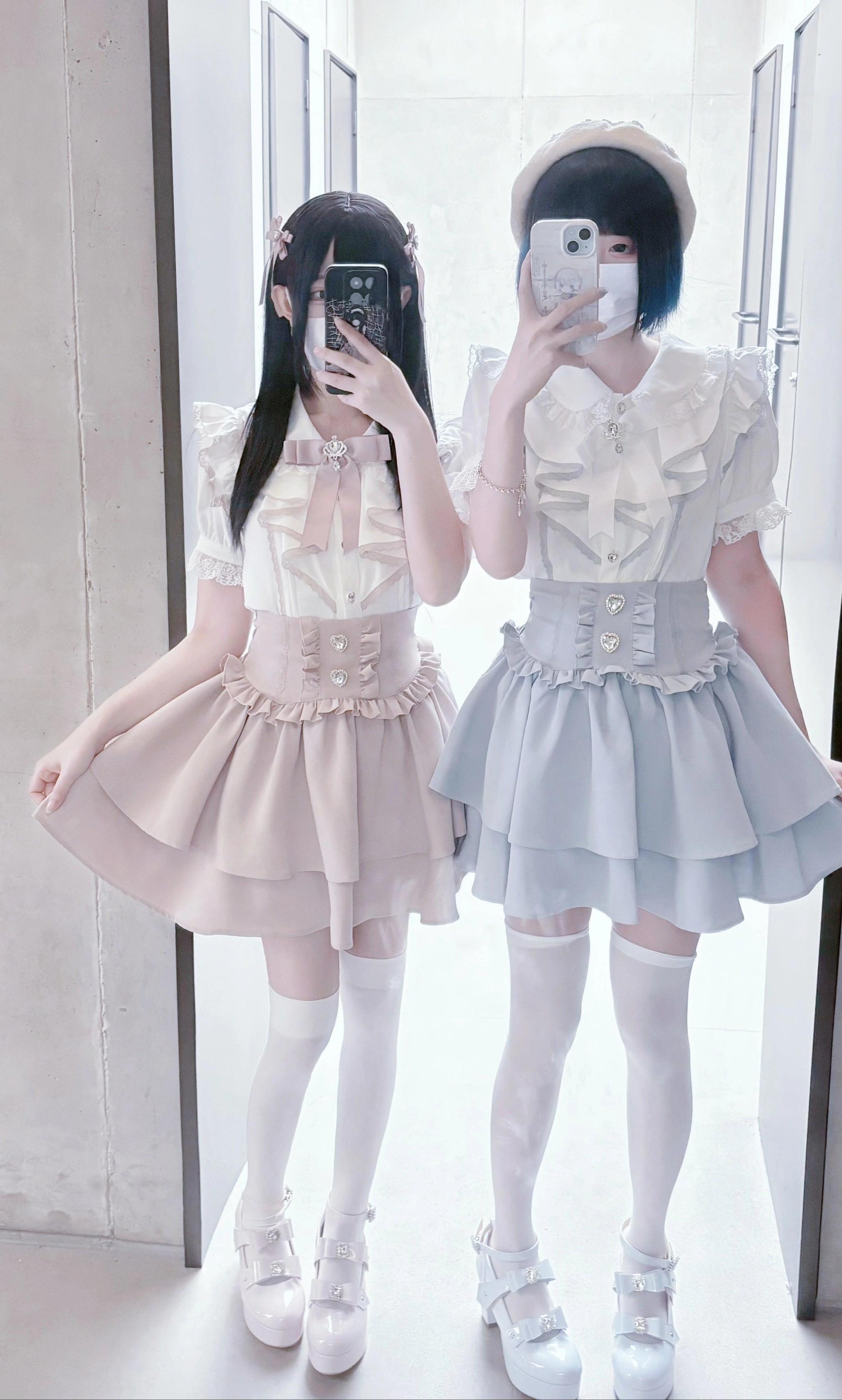 Two real female models in jirai kei two-piece sets with high-waisted corset waistbands, white sheer stockings, full-length boutique mirror selfie
