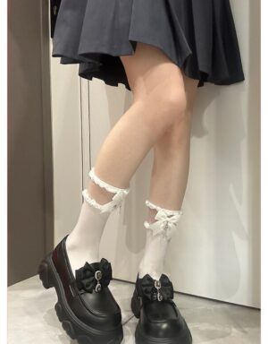 White short Jirai Kei socks with lace ruffled bow cuffs and cross charm side view worn with dark pleated skirt and platform loafers