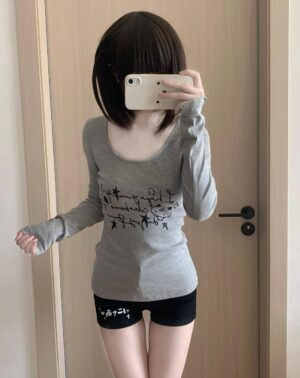 Gray Jirai Kei otaku graphic long-sleeve top with thumbhole cuffs and artistic chest print, worn in mirror selfie showing front styling with black shorts