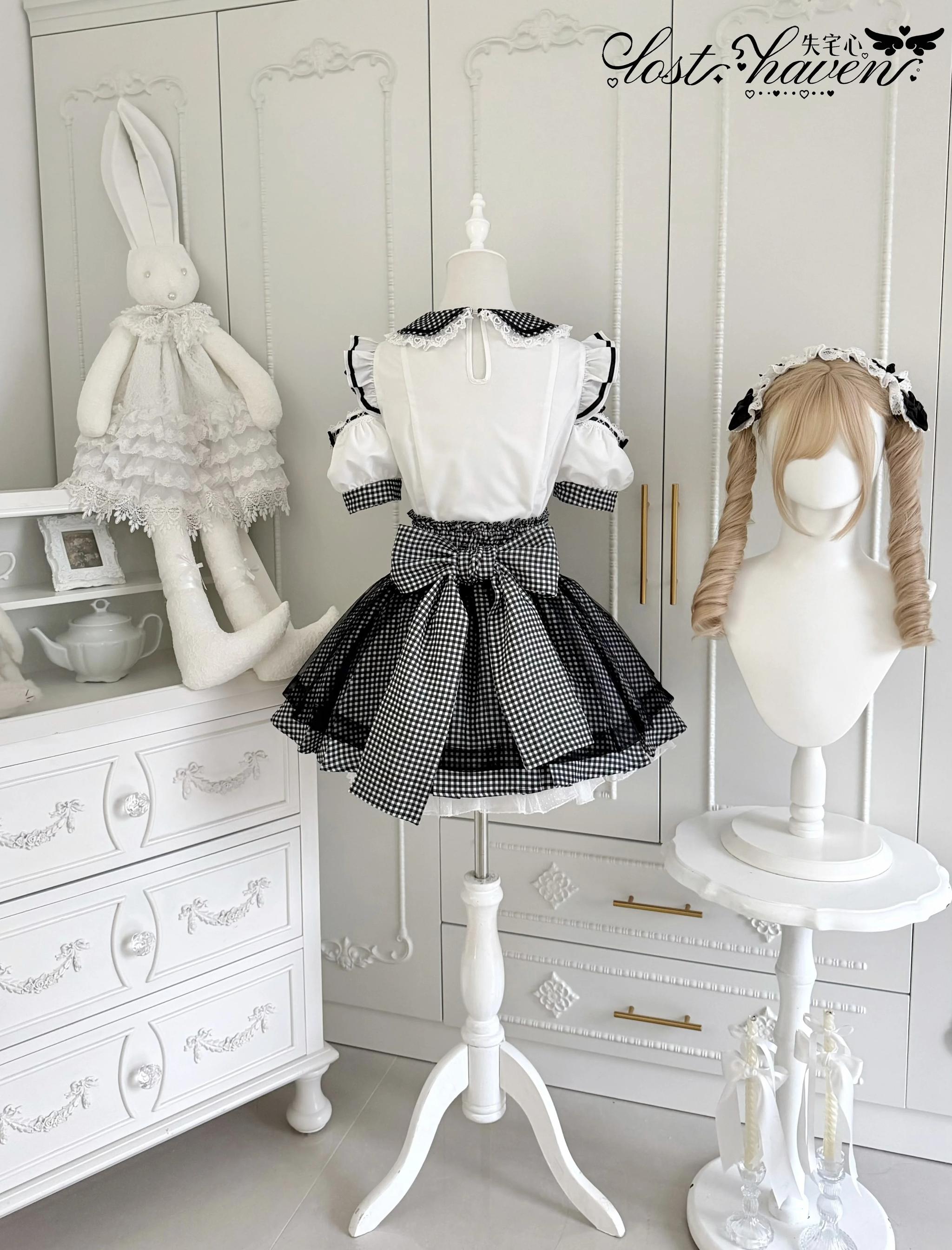 Side-front display view of black and white gingham Jirai Kei maid outfit on mannequin with matching wig, shown in cozy closet with rabbit ornament
