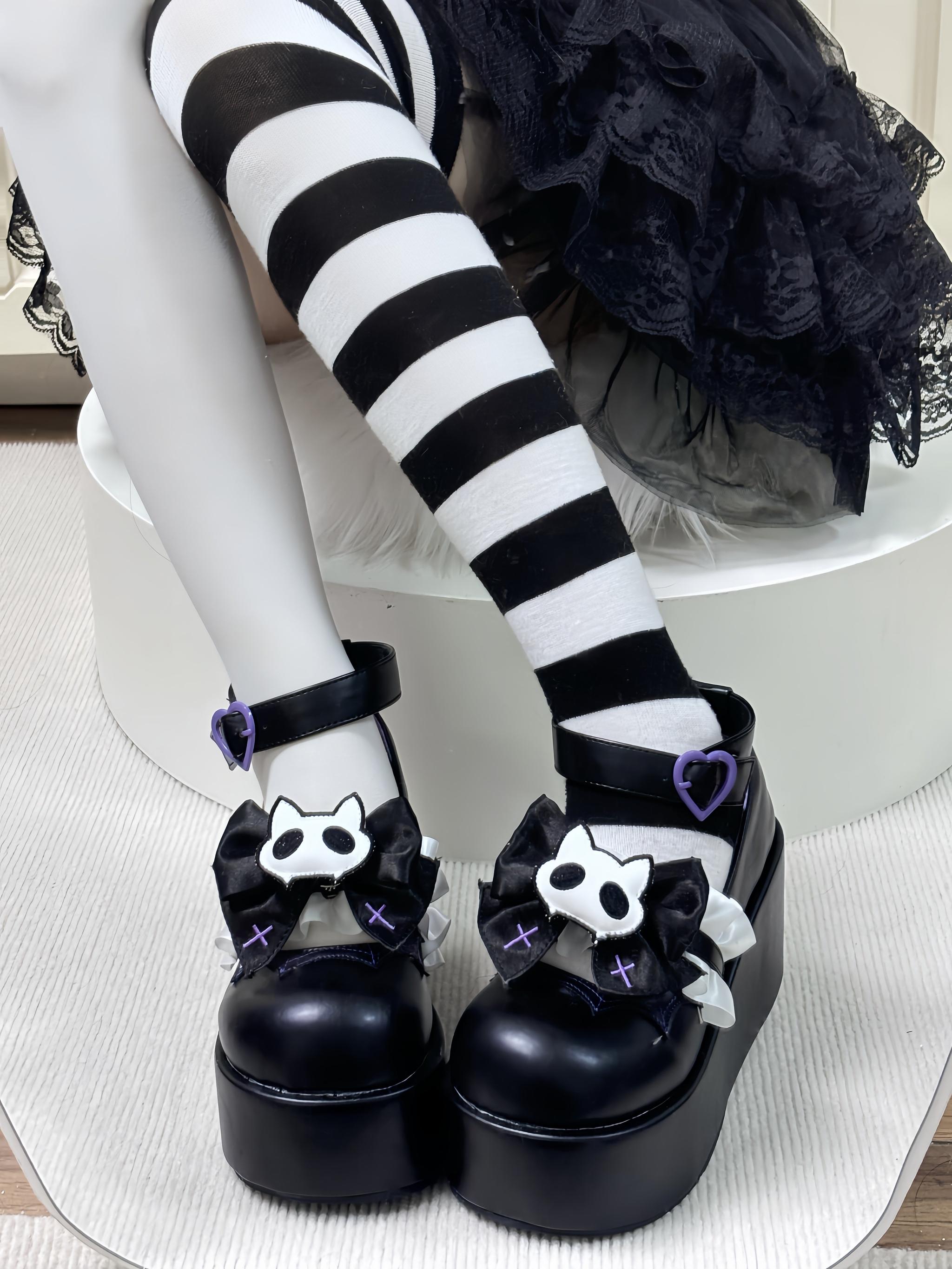 Black gothic platform Mary Jane shoes with purple heart buckle and cat skull bow worn with ruffled skirt and striped stockings front view