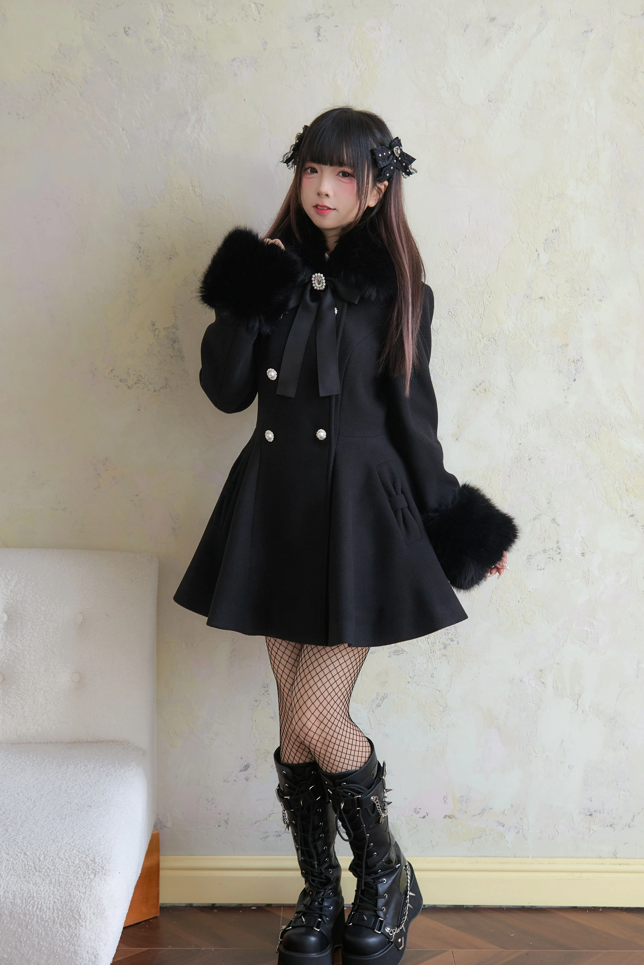 Black mid-length Jirai Kei winter coat side-front angle displaying A-line flared skirt hem and double-breasted pearl buttons