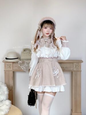 Pink and white ryousangata tweed Lolita dress set worn by model in vintage setting, showing full-body front view with ruffled blouse, heart-appliqued tweed skirt, and coordinated styling