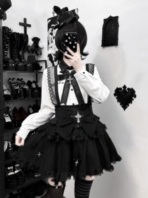 Front-facing gothic Jirai Kei suspender skirt outfit in black and white with cross ornaments and ruffled lace hem, mirror selfie in dark gothic aesthetic setting
