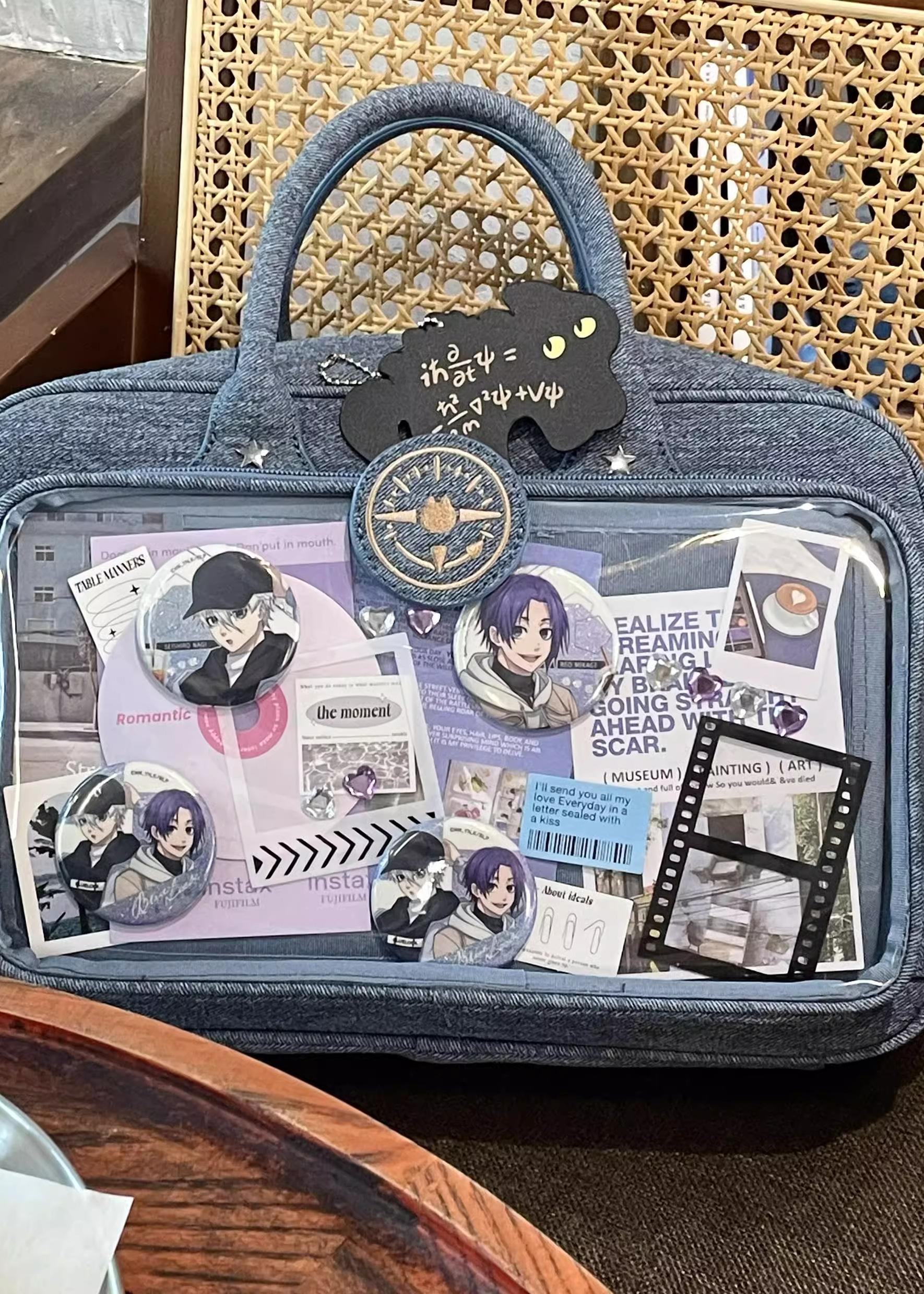 Denim blue Jirai Kei ita shoulder bag close-up front view with film strip and anime print decorations visible through transparent display window