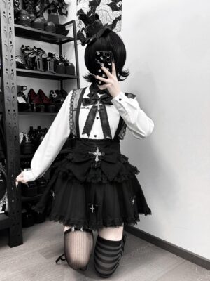 Three-quarter angle mirror selfie of complete Jirai Kei suspender skirt set featuring model wearing mismatched thigh-high socks with black and white gothic outfit