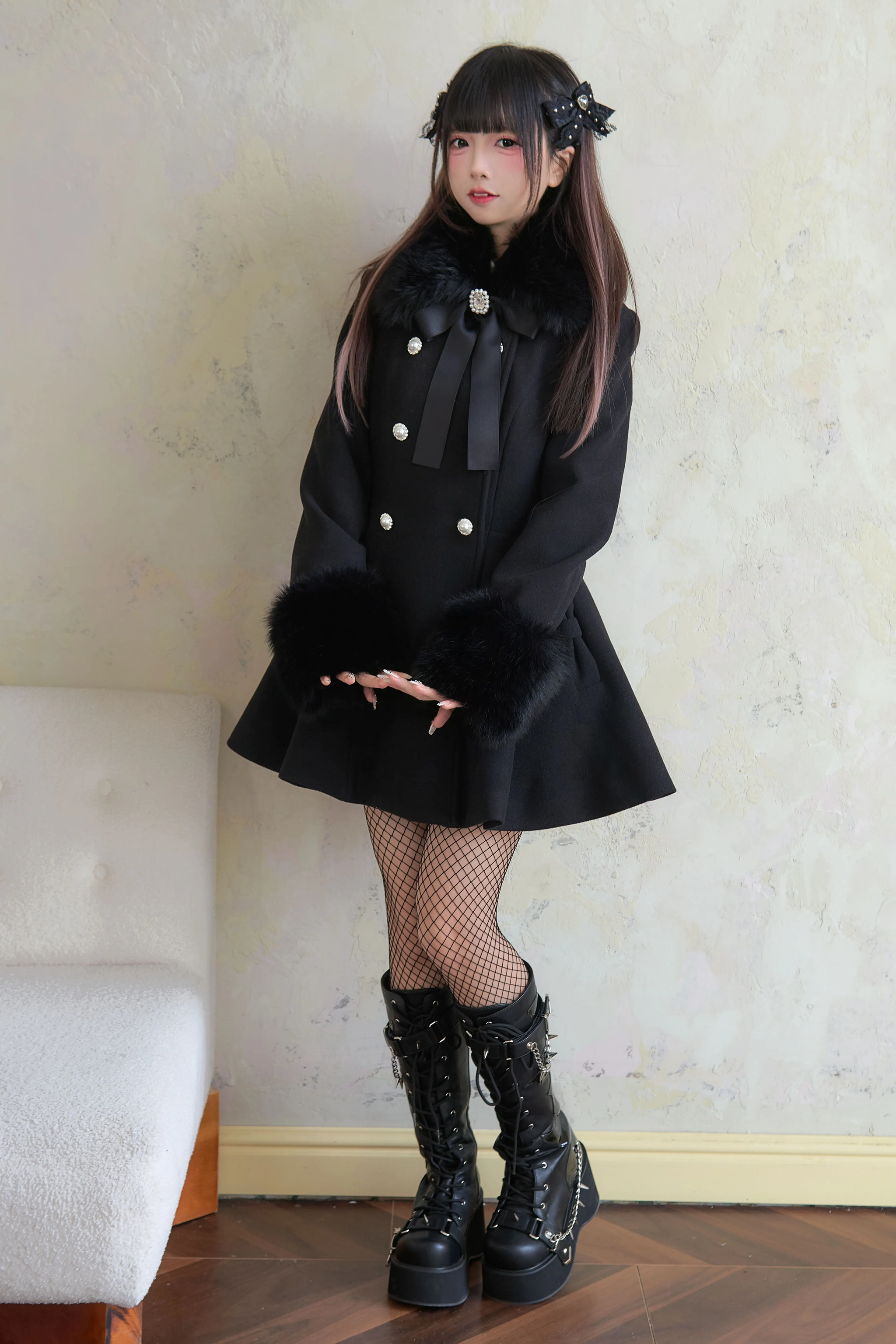 Close-up front full-body view of black Jirai Kei winter coat highlighting pearl decorative buttons neck bow and elegant flared hem