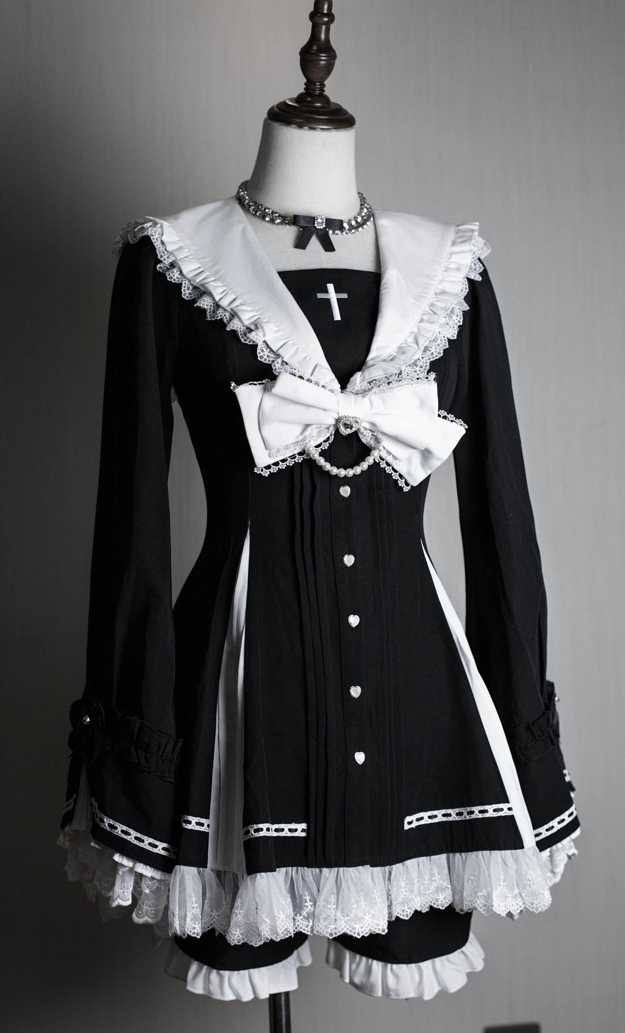 Black and white striped Jirai Kei hime dress with cross accents and delicate lace trim on dress form, showcasing sailor collar and ruffled hem details for dark romantic aesthetic