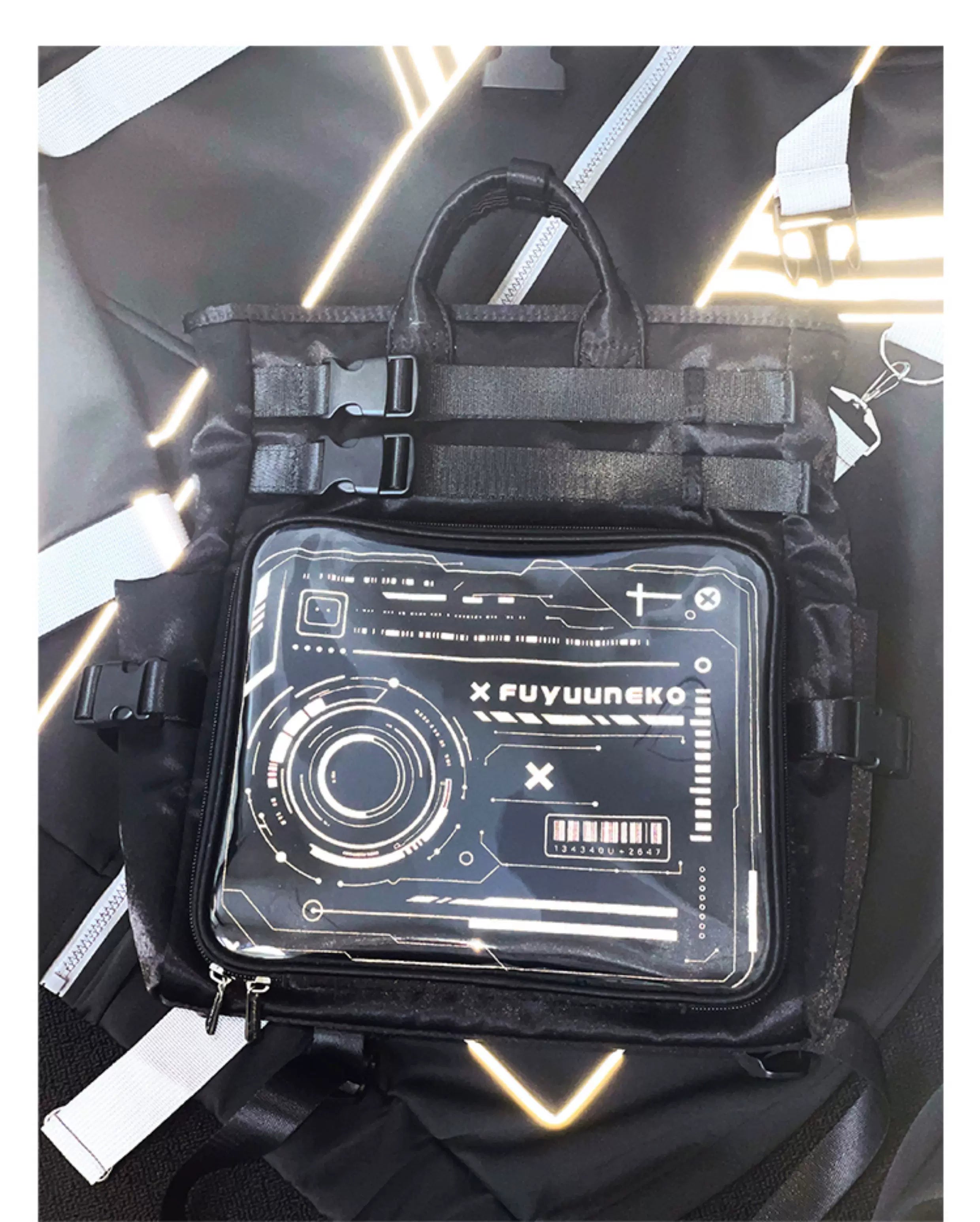 Black cyberpunk ita backpack front flat lay close-up view featuring cyber graphic display window with webbing buckle straps and reinforced handles on tech background