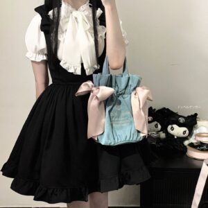 White Jirai Kei blouse with detachable black satin bow tie and puffed short sleeves paired with black suspender skirt, styled with Kuromi plushies and coordinating tote bag