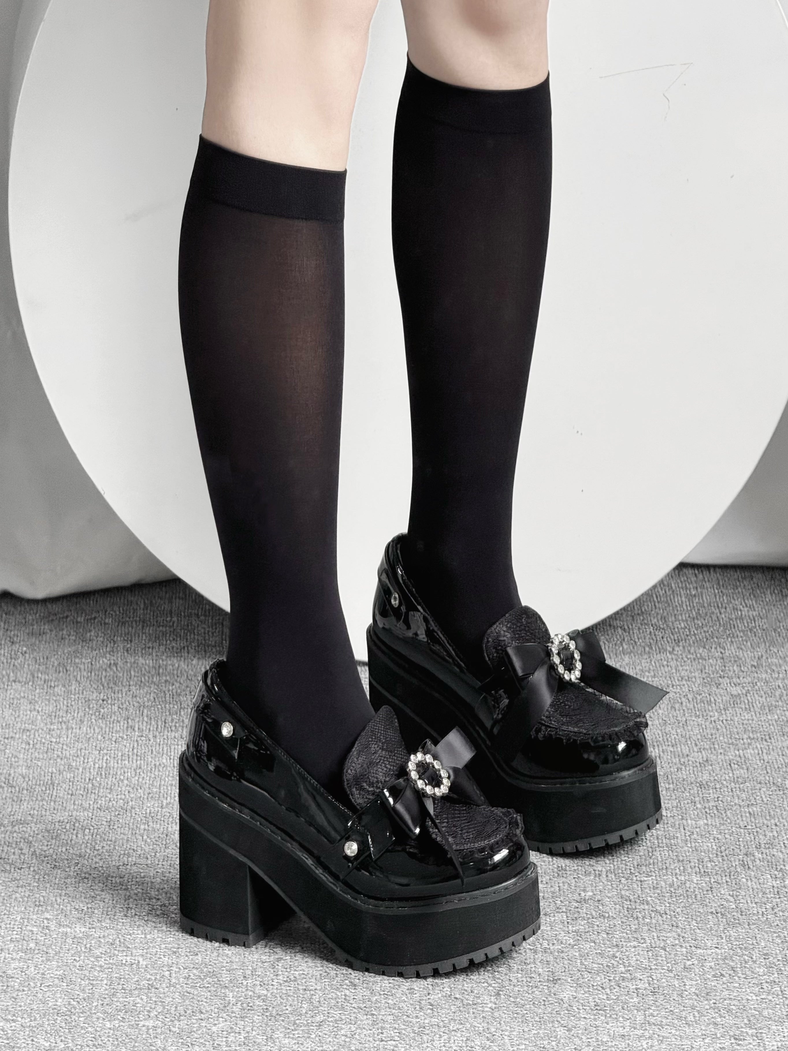 Black knee-high Jirai Kei socks side-front angle showing elegant leg silhouette with platform shoes