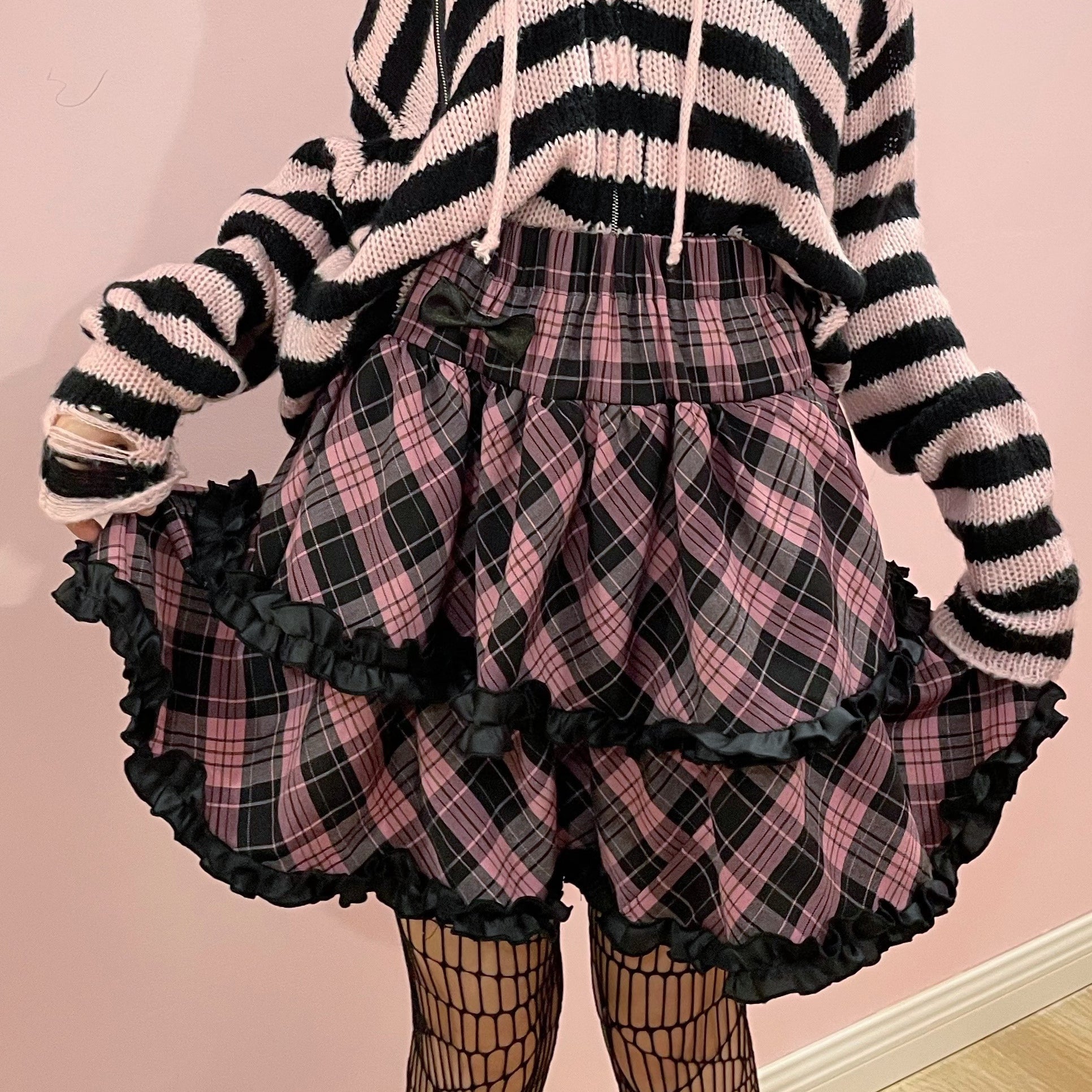 Close-up detail of pink-black plaid Jirai Kei ruffle skirt showing black frilled trim, high waist elastic band, and puffed silhouette