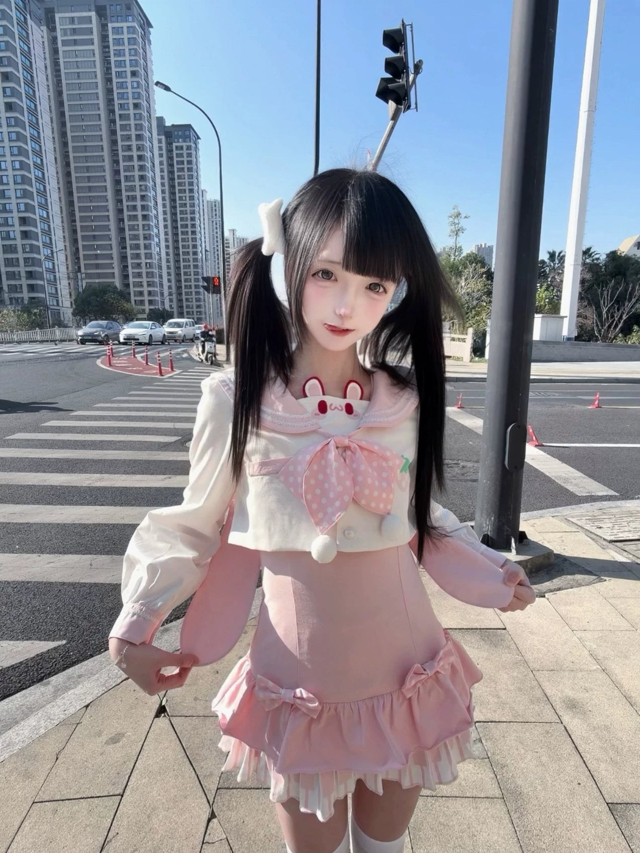 Detachable long-sleeve sailor collar blouse with bunny ear neckline decoration and removable polka-dot bow, ruffle hem pink skirt, side profile on city crosswalk with twin-tailed model