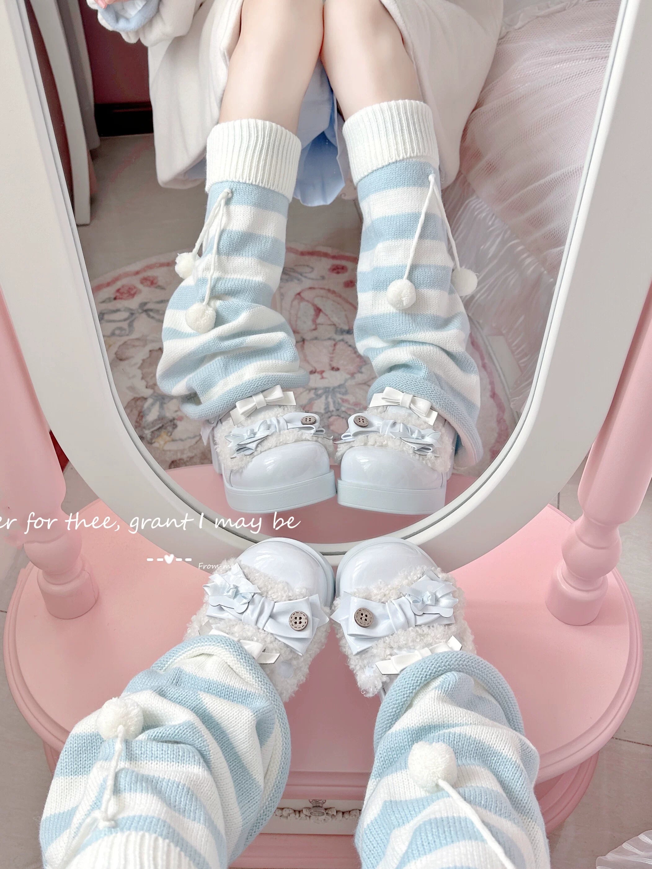 Mirror back view of light blue and white striped leg warmers with fluffy pompom cuffs and close-up of feet with white platform loafers in pink room