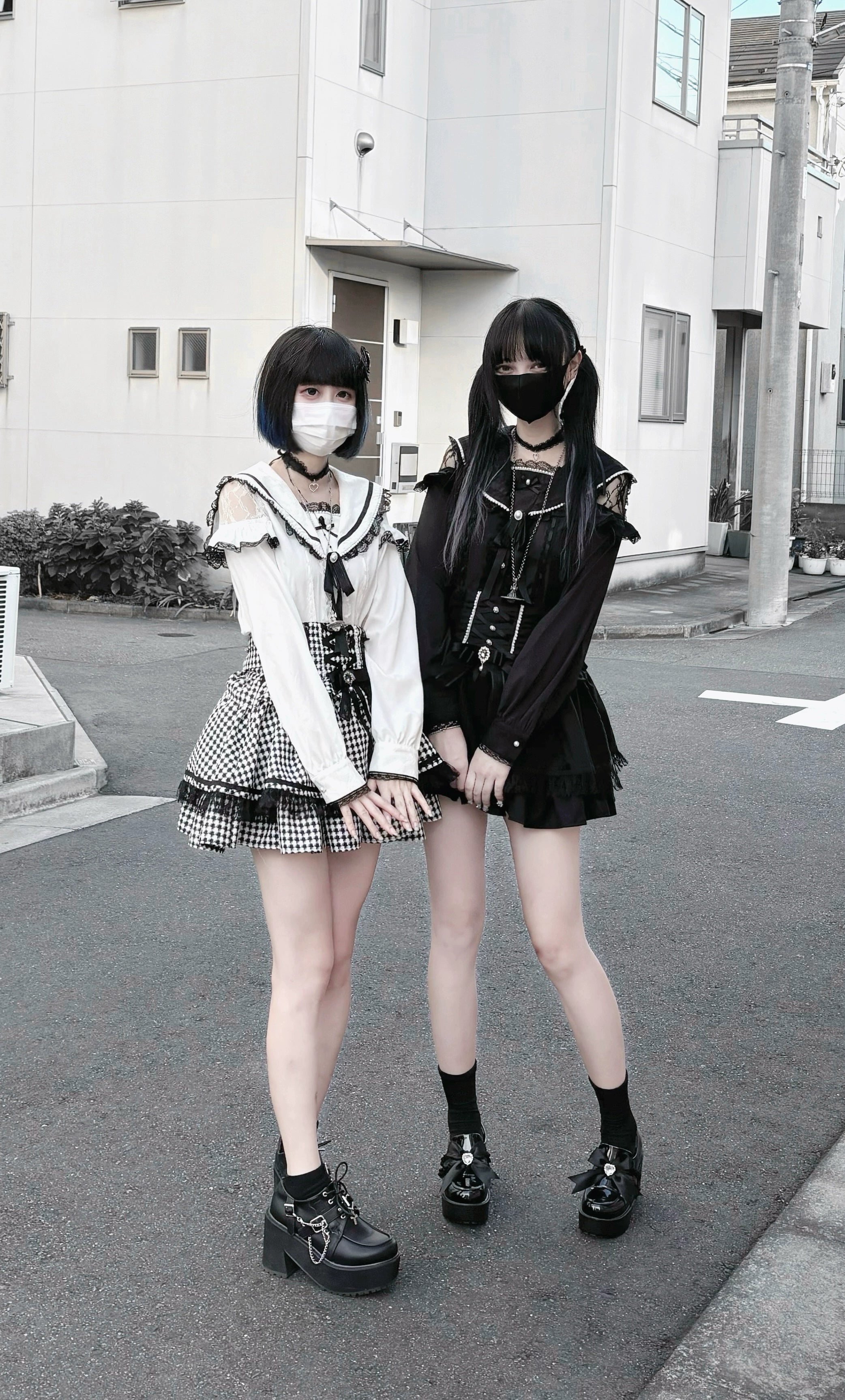Pair of masked female models in Jirai Kei outfits featuring white off-shoulder sailor collar top with black gothic styling ensemble, demonstrating versatile layering options with sailor blouse as core piece