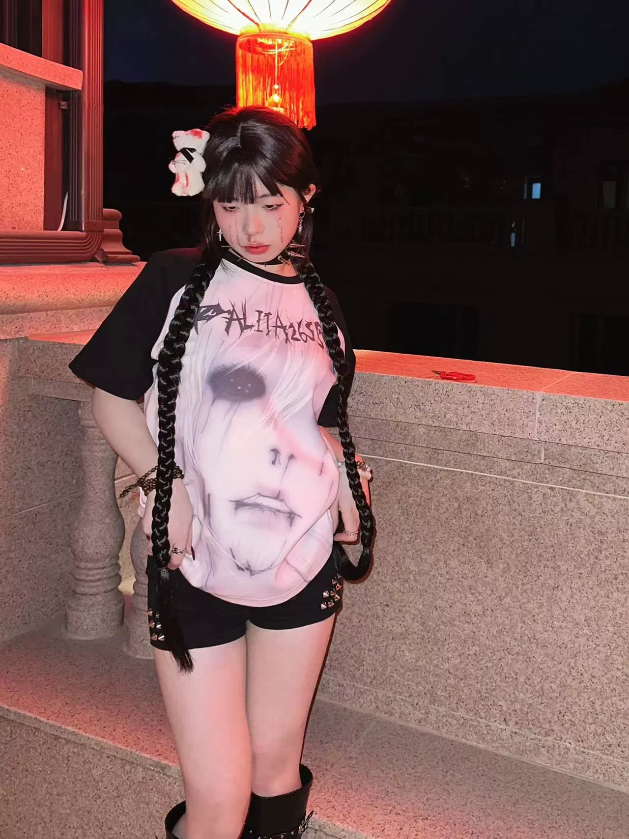 Model wearing Jirai Kei raglan printed T-shirt with dark anime character graphic and black contrast sleeves in balcony setting