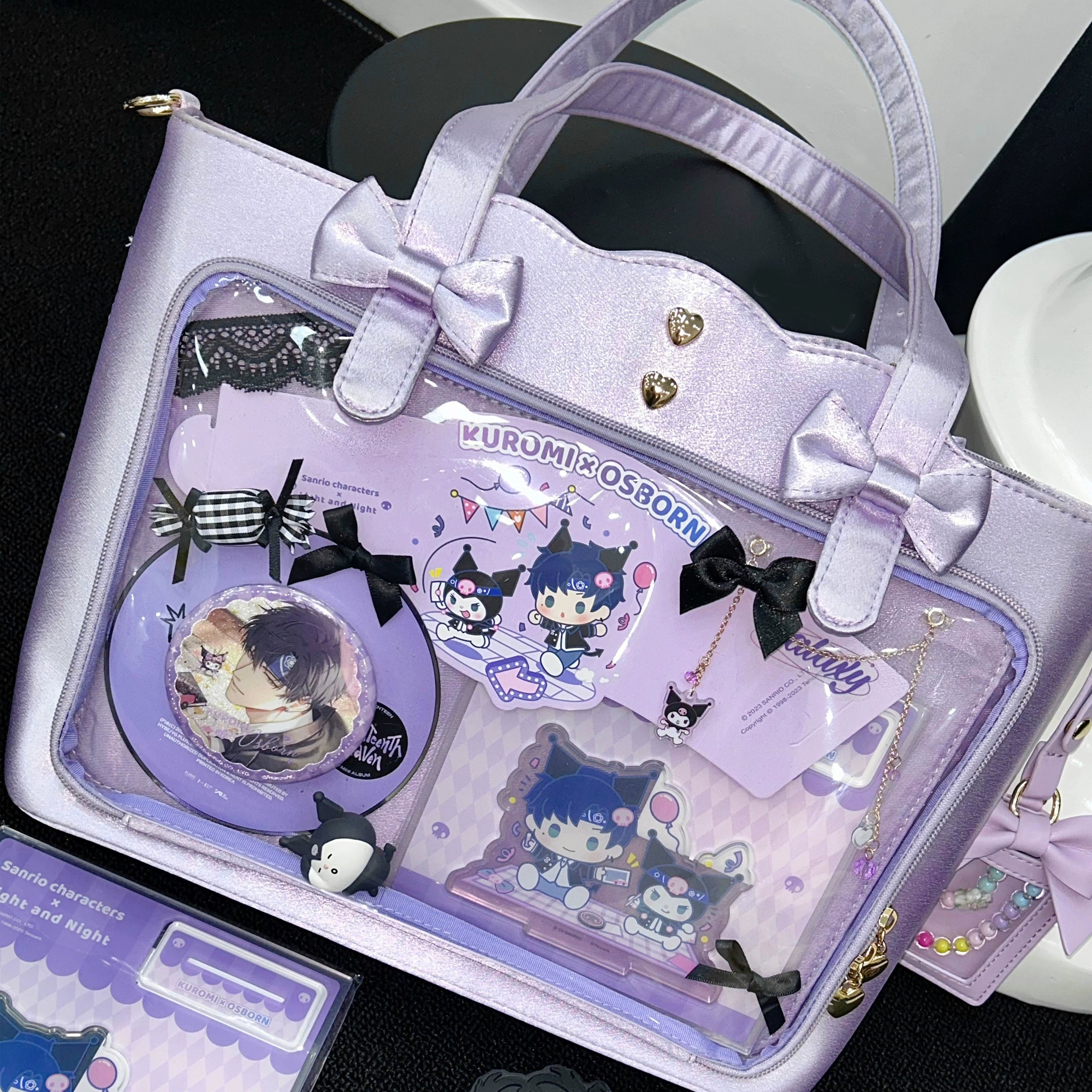 Light purple Jirai Kei ita bag front overhead display on tabletop, featuring Kuromi themed decorative elements, bow accent details, delicate lace trim embellishment, and attached charm accessories