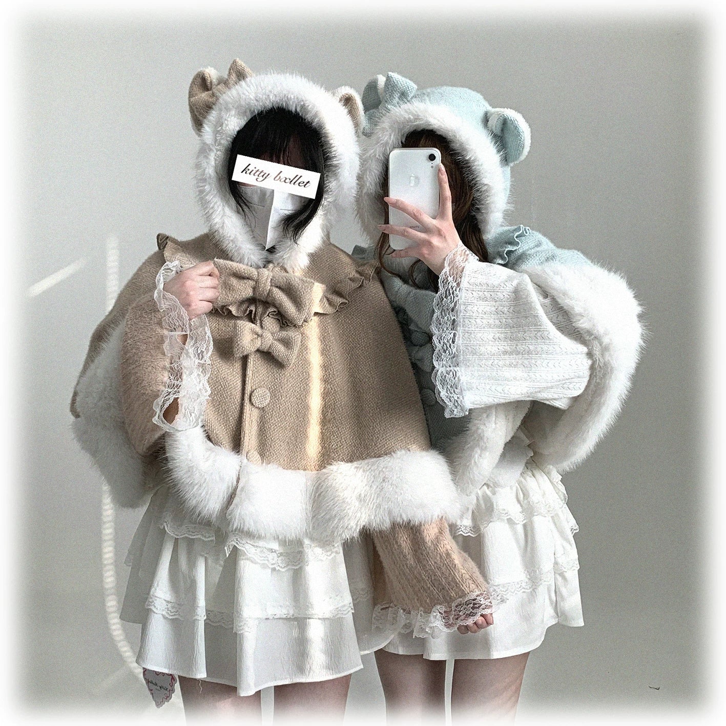 Self-taken casual close-up of light blue cat-ear cape worn with black top, showcasing white fuzzy trim and front bow paired with ruffled handbag