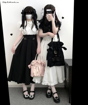 Full-body front view of black and white Jirai Kei twin skirt sets featuring heart-shaped buckles and ruffled hemlines worn by two models in coordinated studio setting