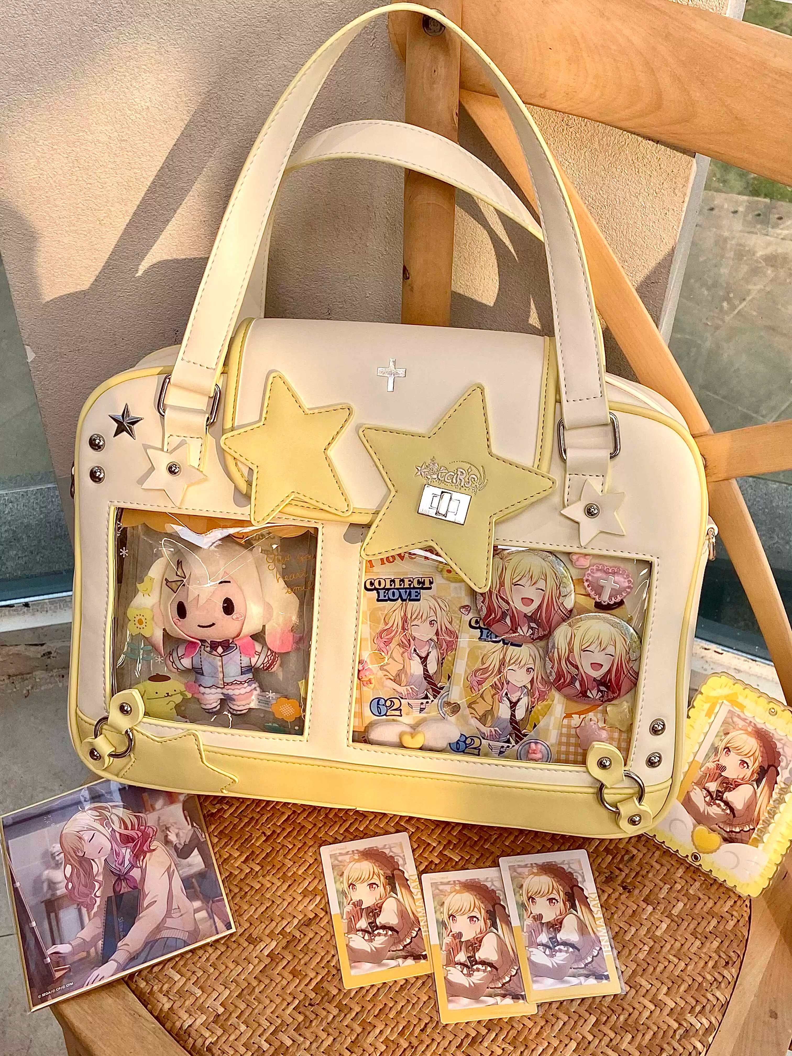 Beige yellow star Jirai Kei itabag front view on wooden chair with anime trading cards and collectibles