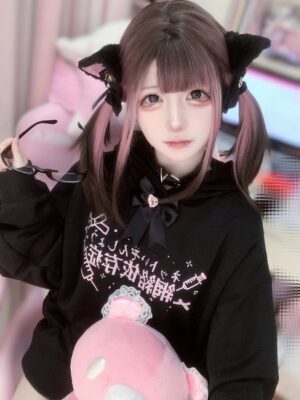 Black Tenshi Kaiwai oversized Jirai Kei hoodie with heart-shaped bow and gothic Japanese text, model wearing cat ear hair clips and two-tone twin tails, close-up front shot