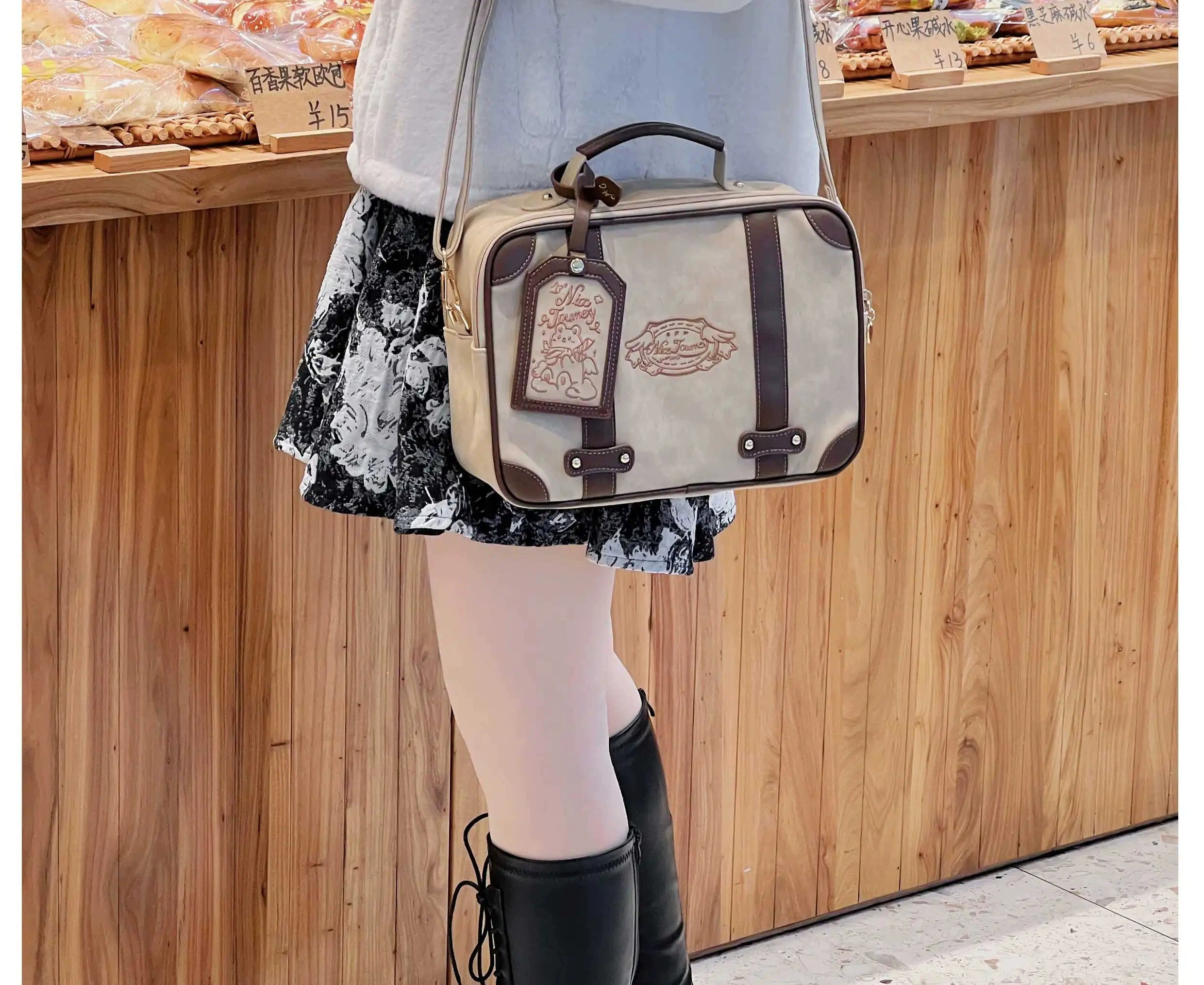 Vintage square itabag side three-quarter view indoor shop model leather shoulder strap branded luggage tag neutral color scheme structured shape