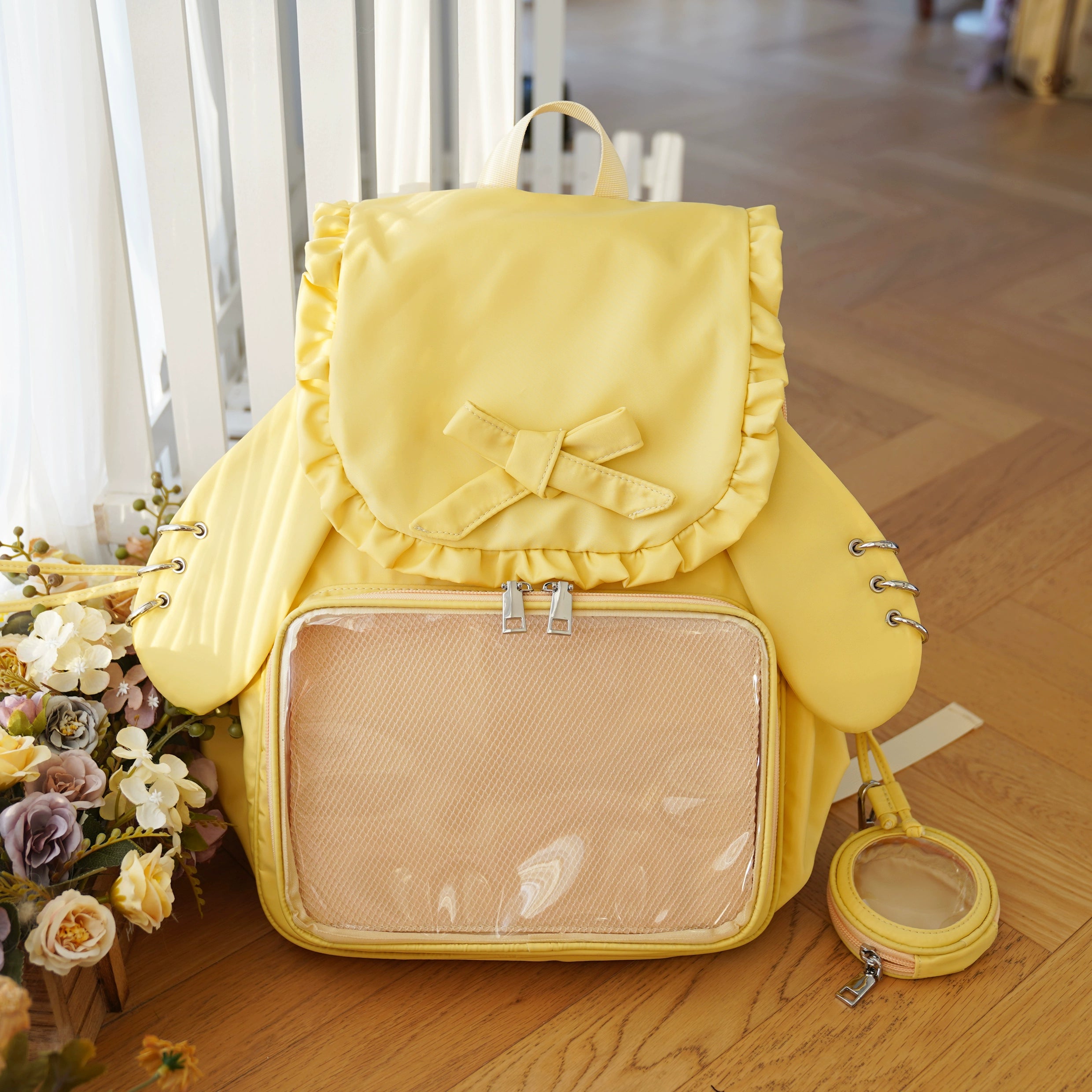 Butter yellow Jirai Kei itabag backpack featuring ruffled bow trim, transparent badge display pocket, and coordinating yellow round pouch