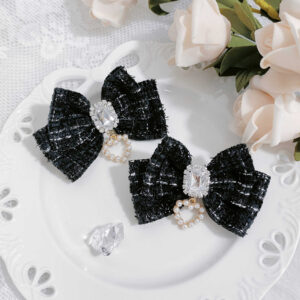Classic black tweed Jirai Kei bow hair clip set with rhinestone and heart-shaped pearl pendant, displayed on white decorative tray with pink roses and crystal accents, top-down flat lay view