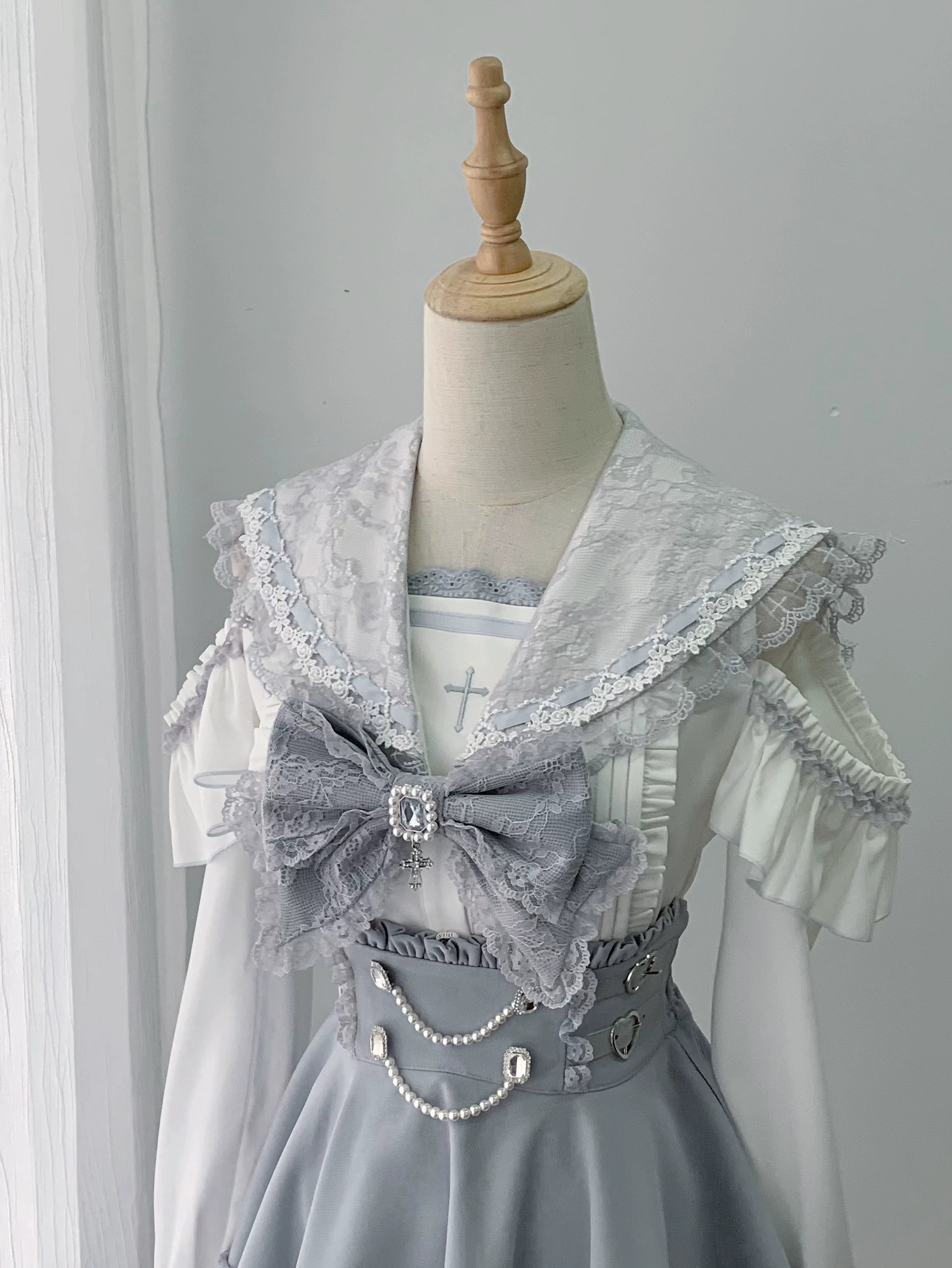 Long sleeve ryousangata sailor jirai kei blouse with bow tie in ivory and light grey featuring cold-shoulder neckline lace trim and button closure front view