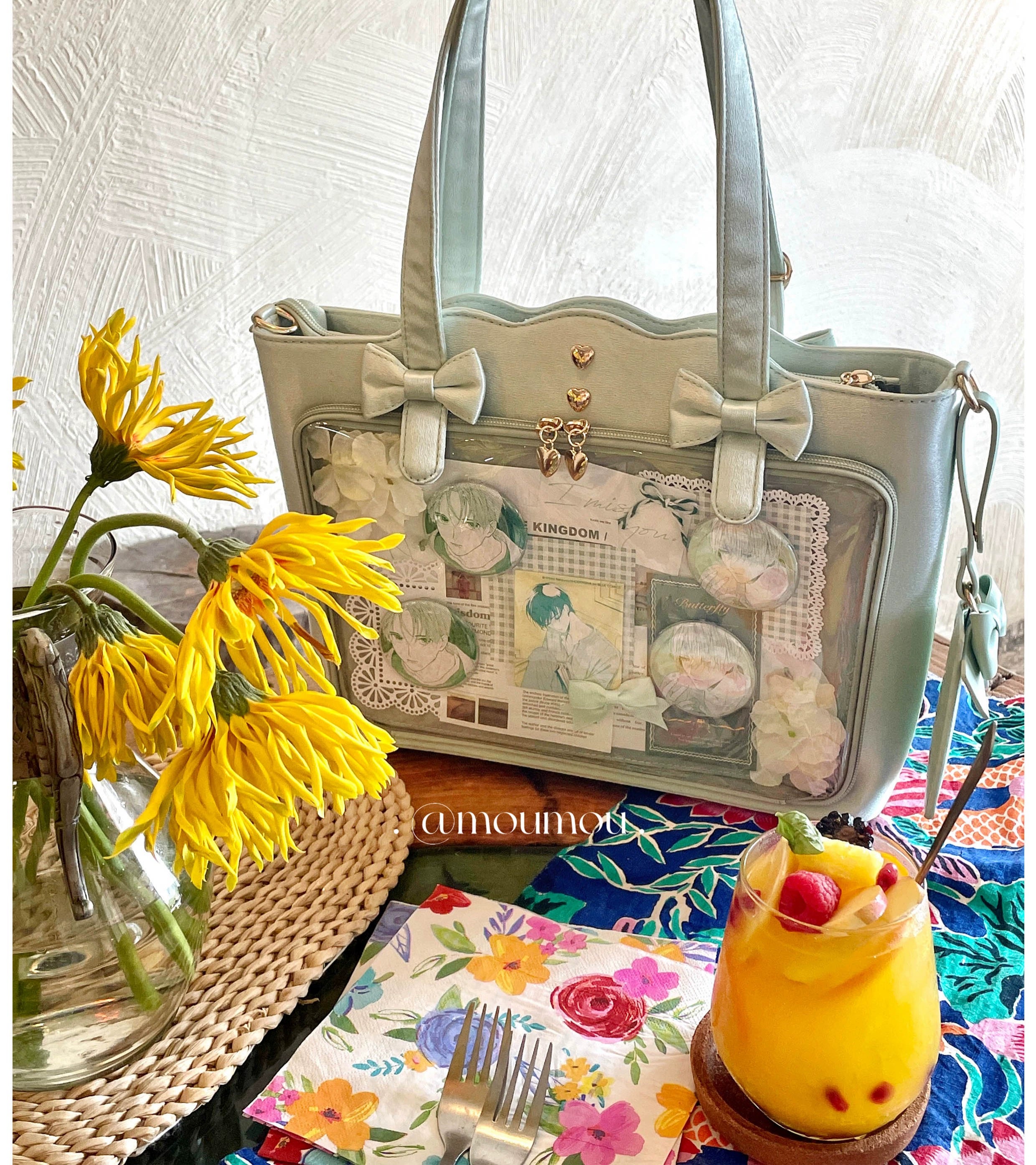 Jirai Kei ita bag close-up detail view showing transparent display window quality, heart-shaped metal studs craftsmanship, bow decoration stitching, and removable shoulder strap attachment mechanism
