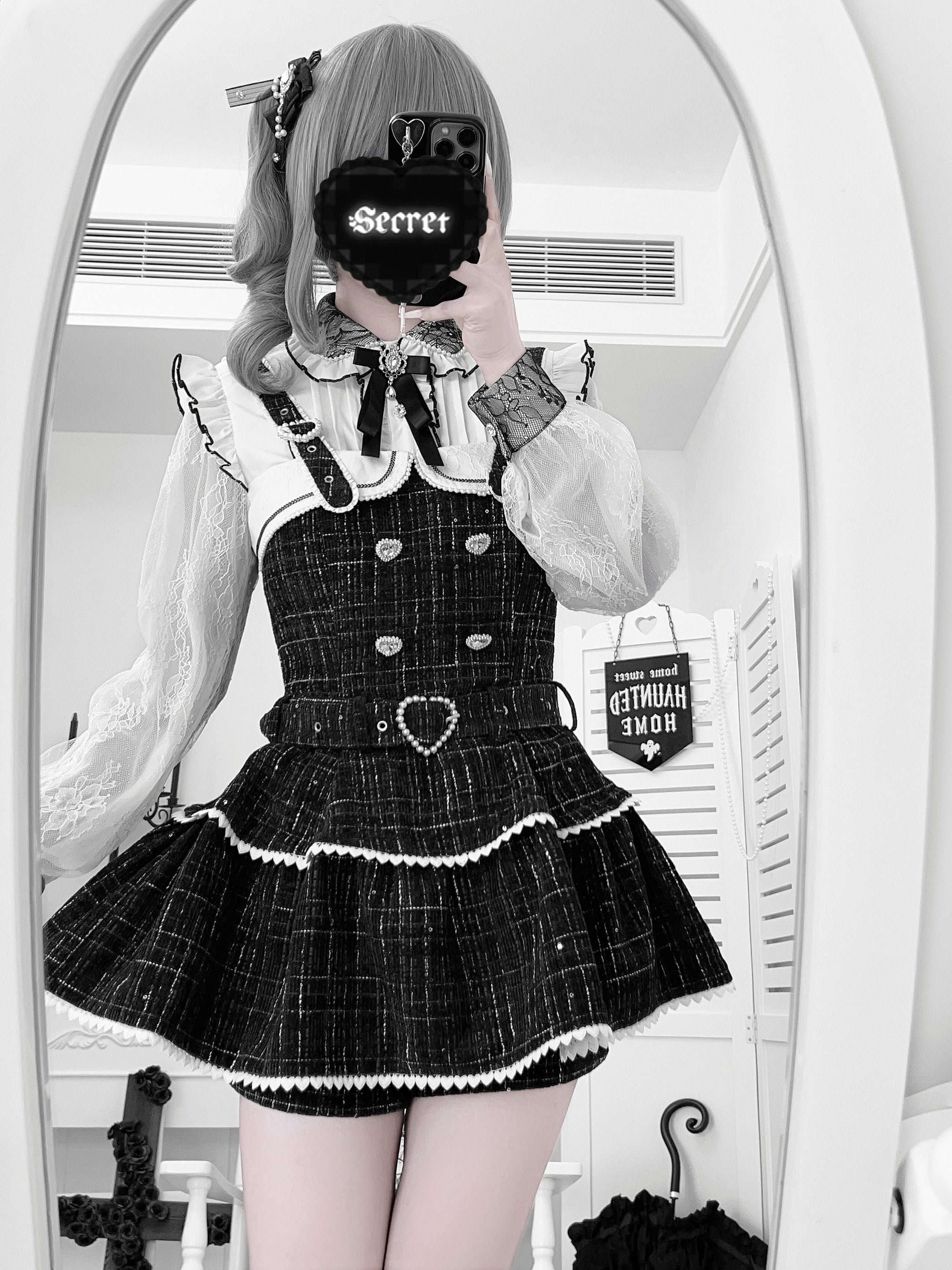 Black Jirai Kei suspender skirt mirror selfie with heart-shaped waist buckle, tiered ruffled skirt, twin-tail styling